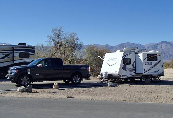 a truck and camper on a paved site with sparse vegetation