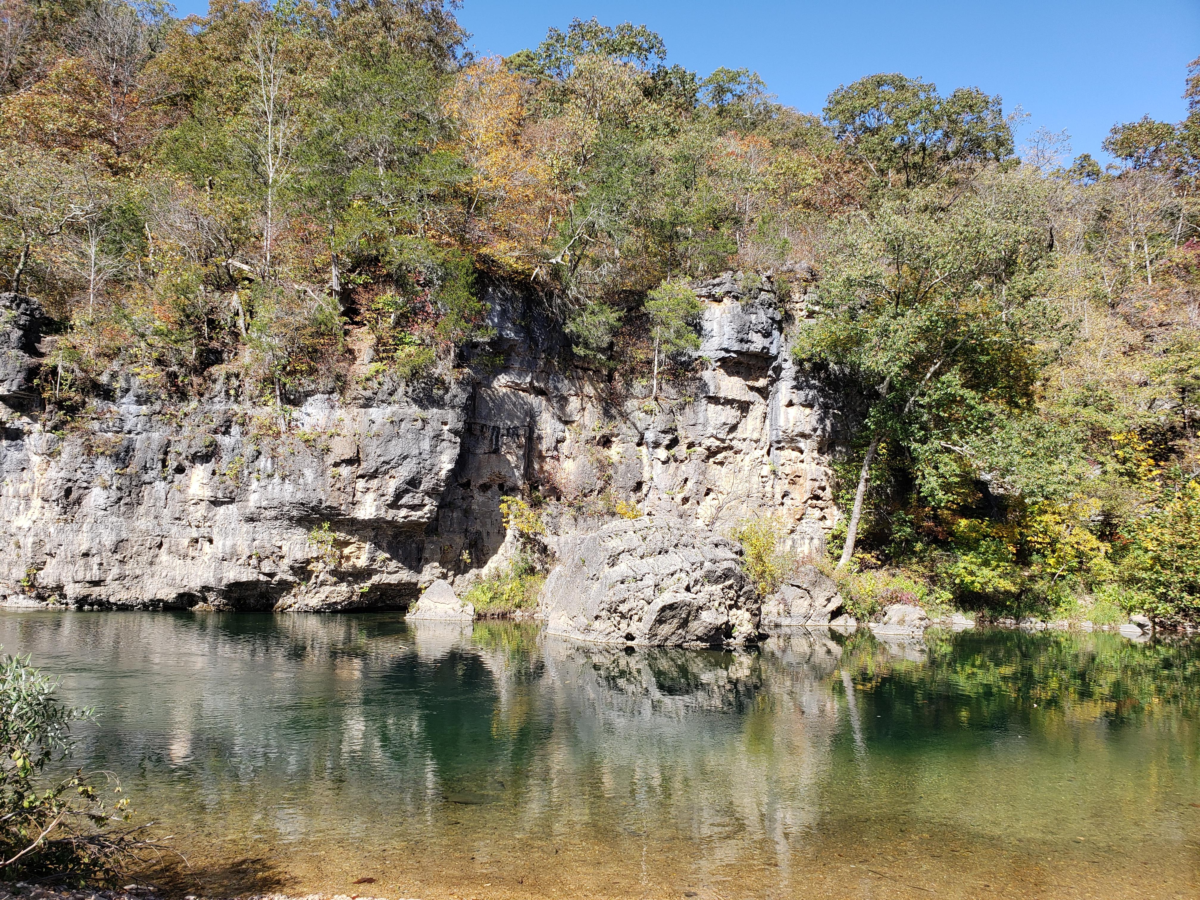 A large boulder stands over a deep, blue pool of the Jacks Fork River.