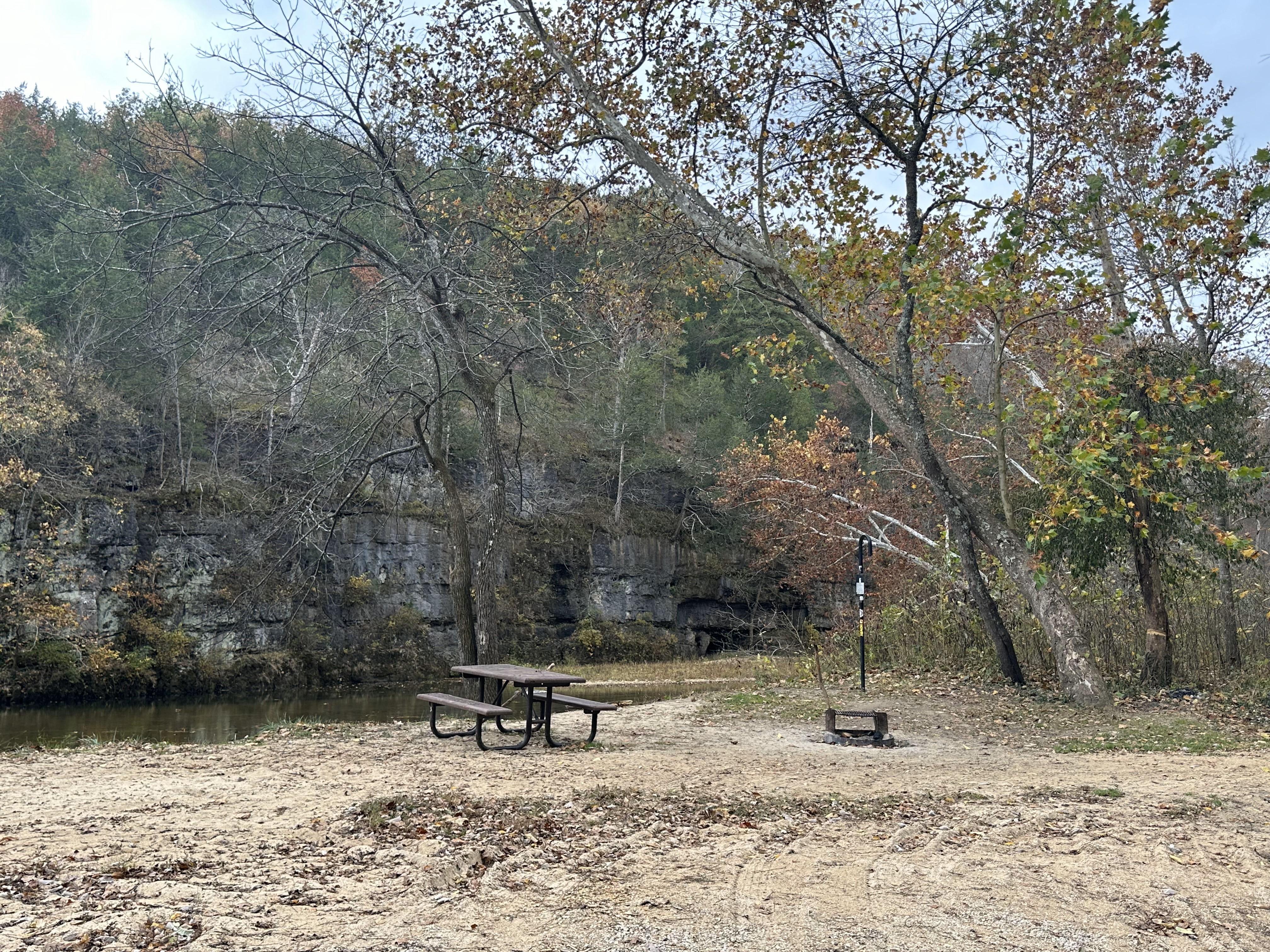 A riverside campsite facing a large stone bluff.
