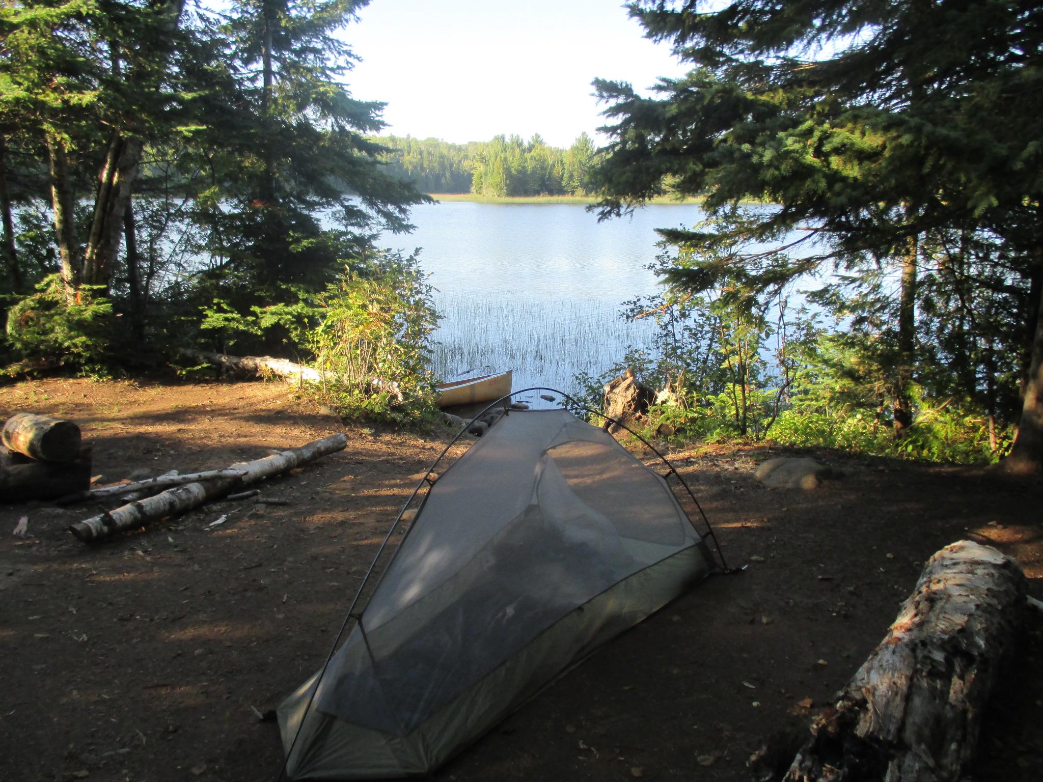 Tent on the shores of Chickenbone Lake with trees along the shoreline.