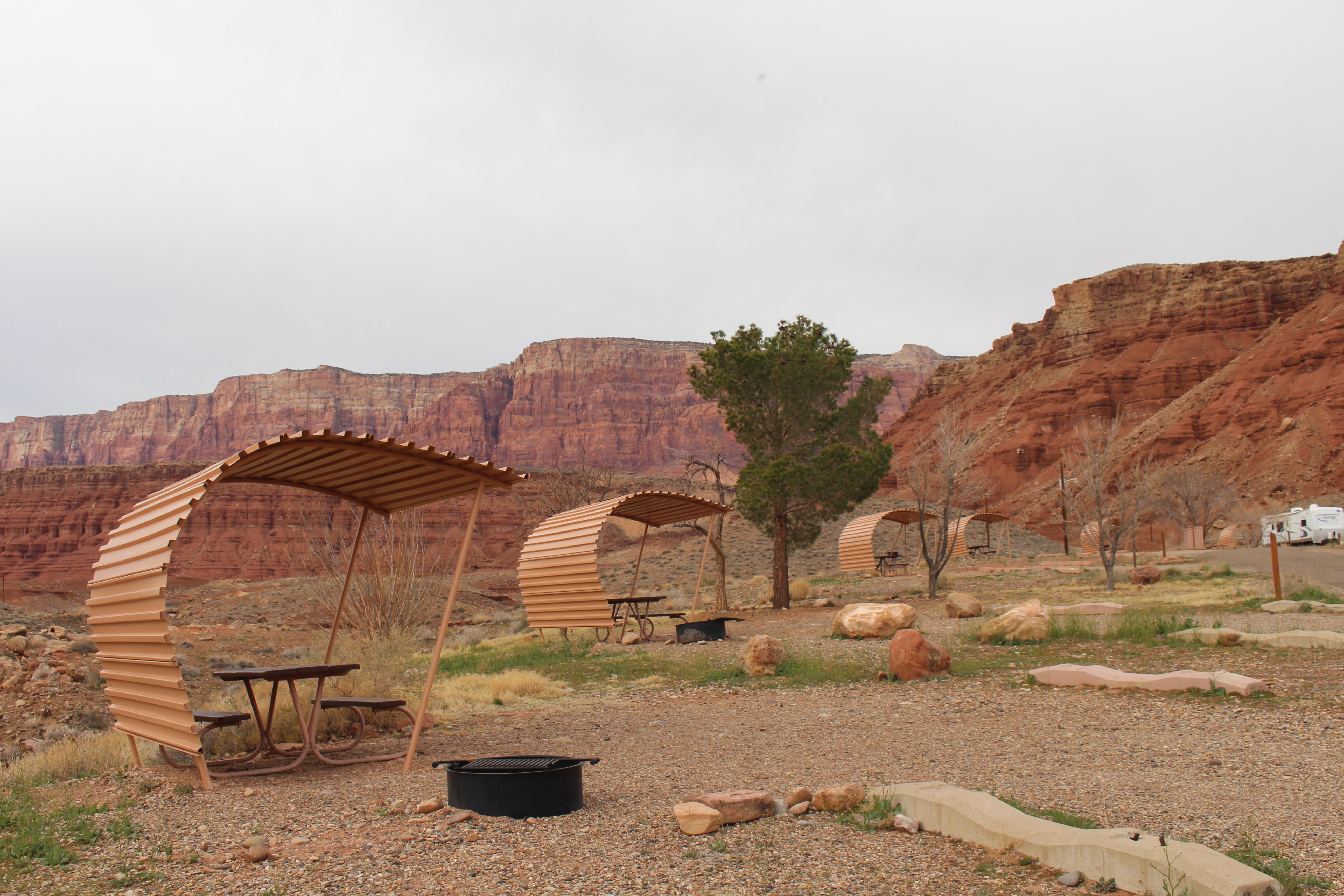 Row of curved shade structures at campsites, RV in background