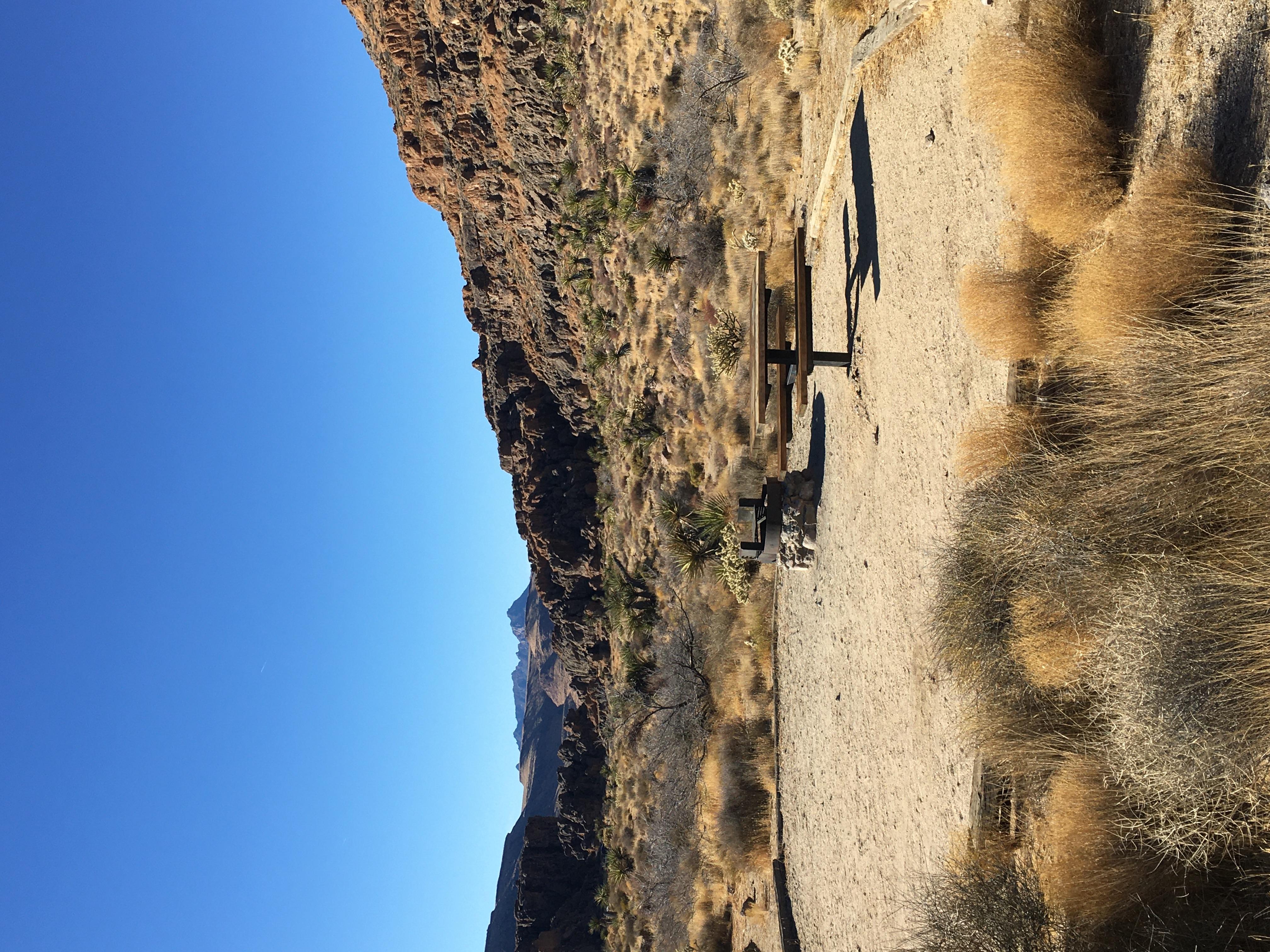 A campsite: cleared area, raised fire pit, picnic table, rock formations, desert shrubbery