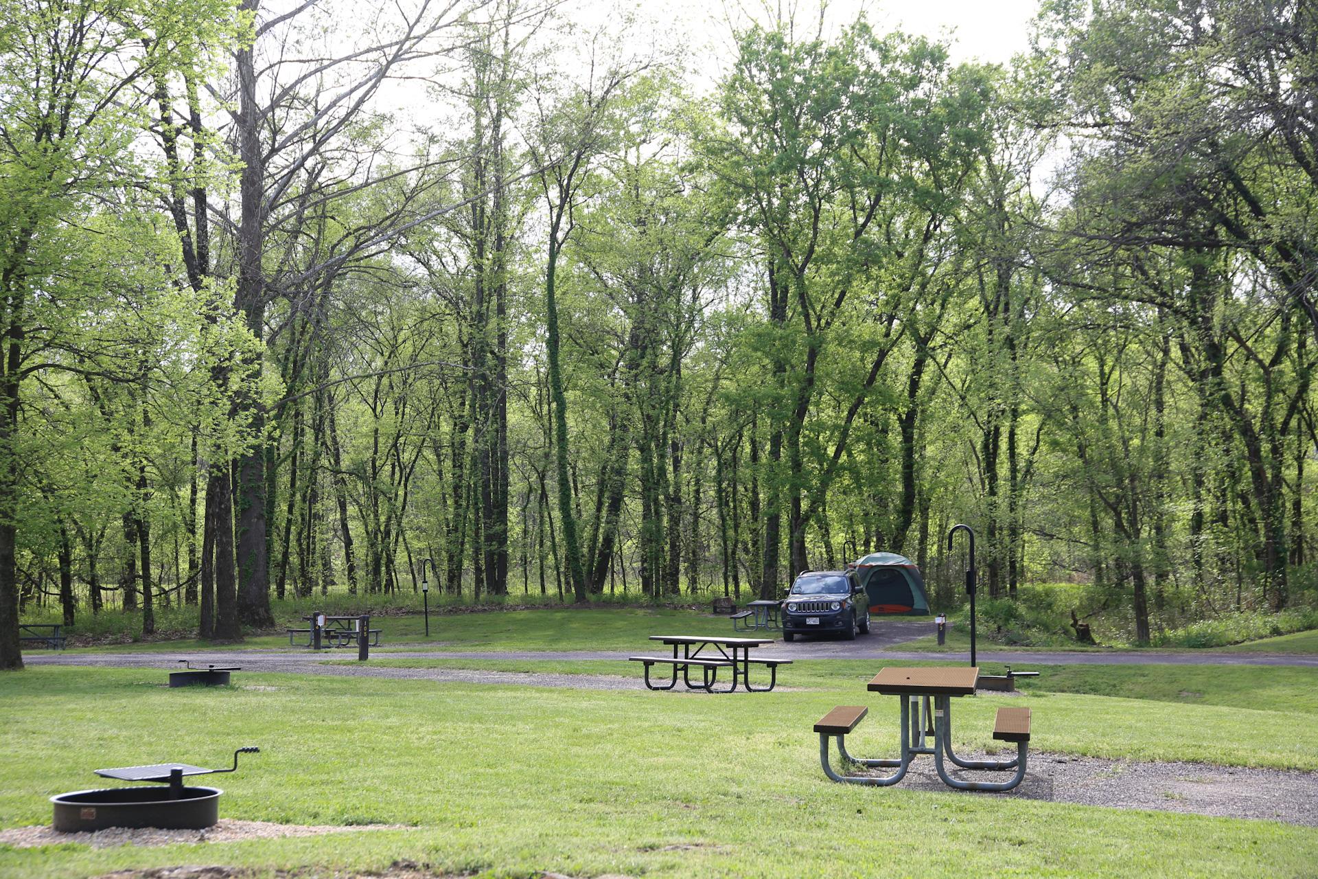 A car and tent occupy a campsite in a campground loop.