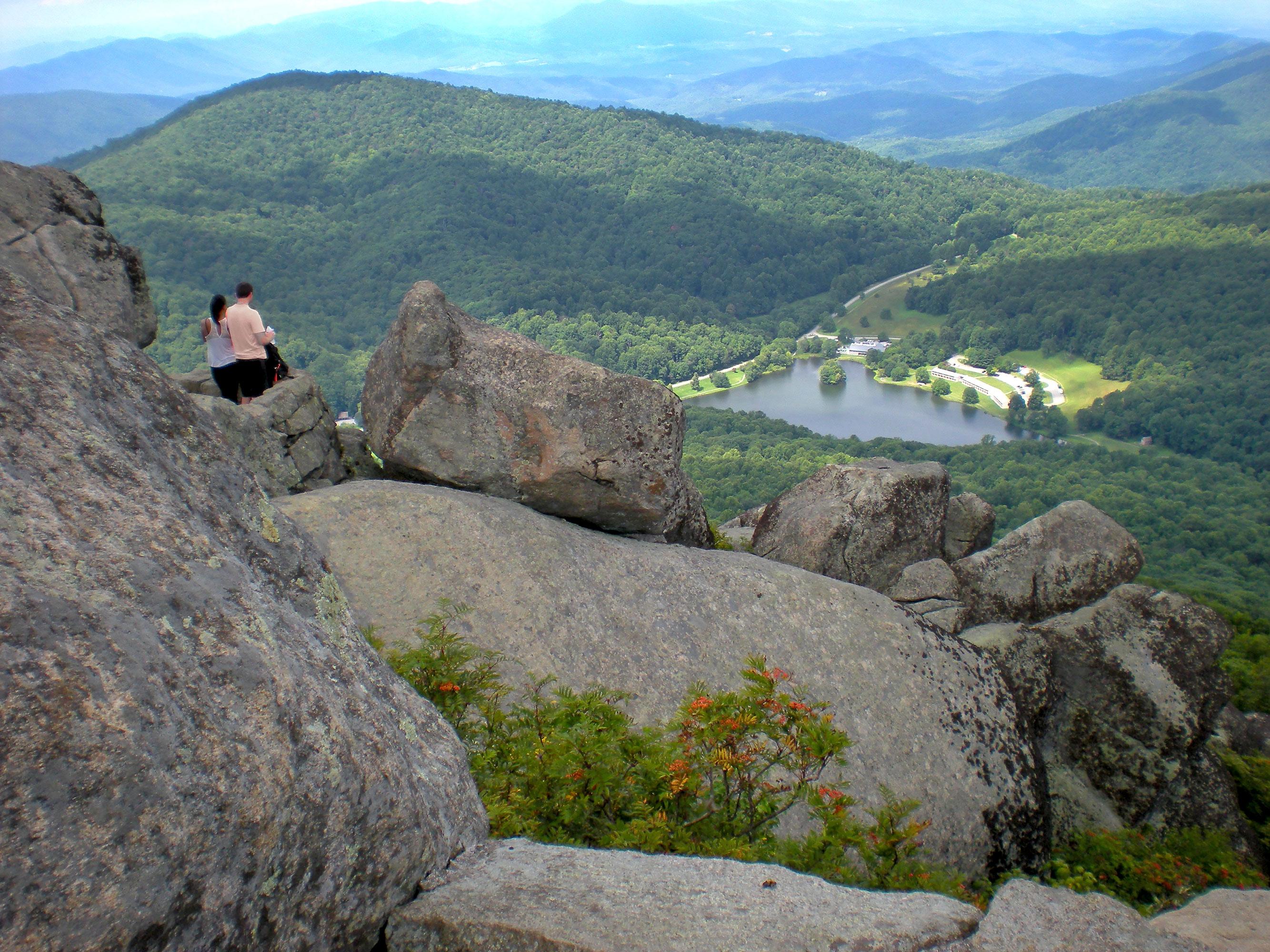 Two hikers standing among large boulders at the top of a mountain