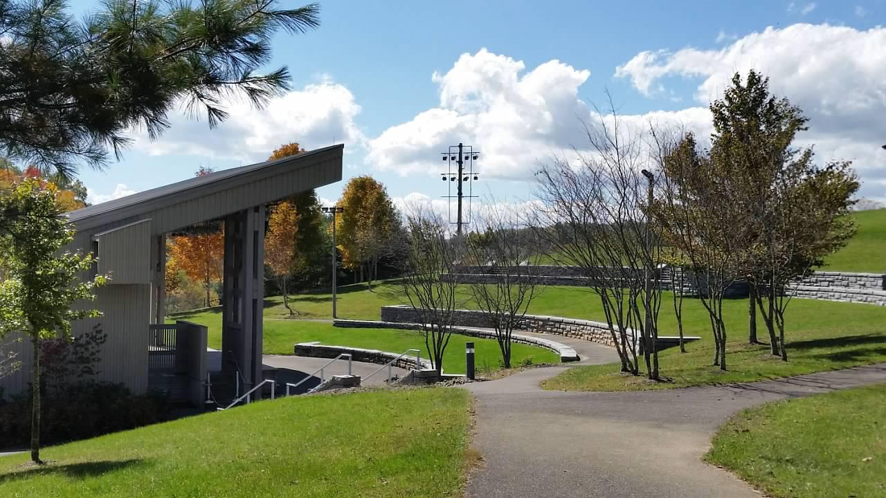 A grassy amphitheater sits in front of an open-fronted building with a covered stage
