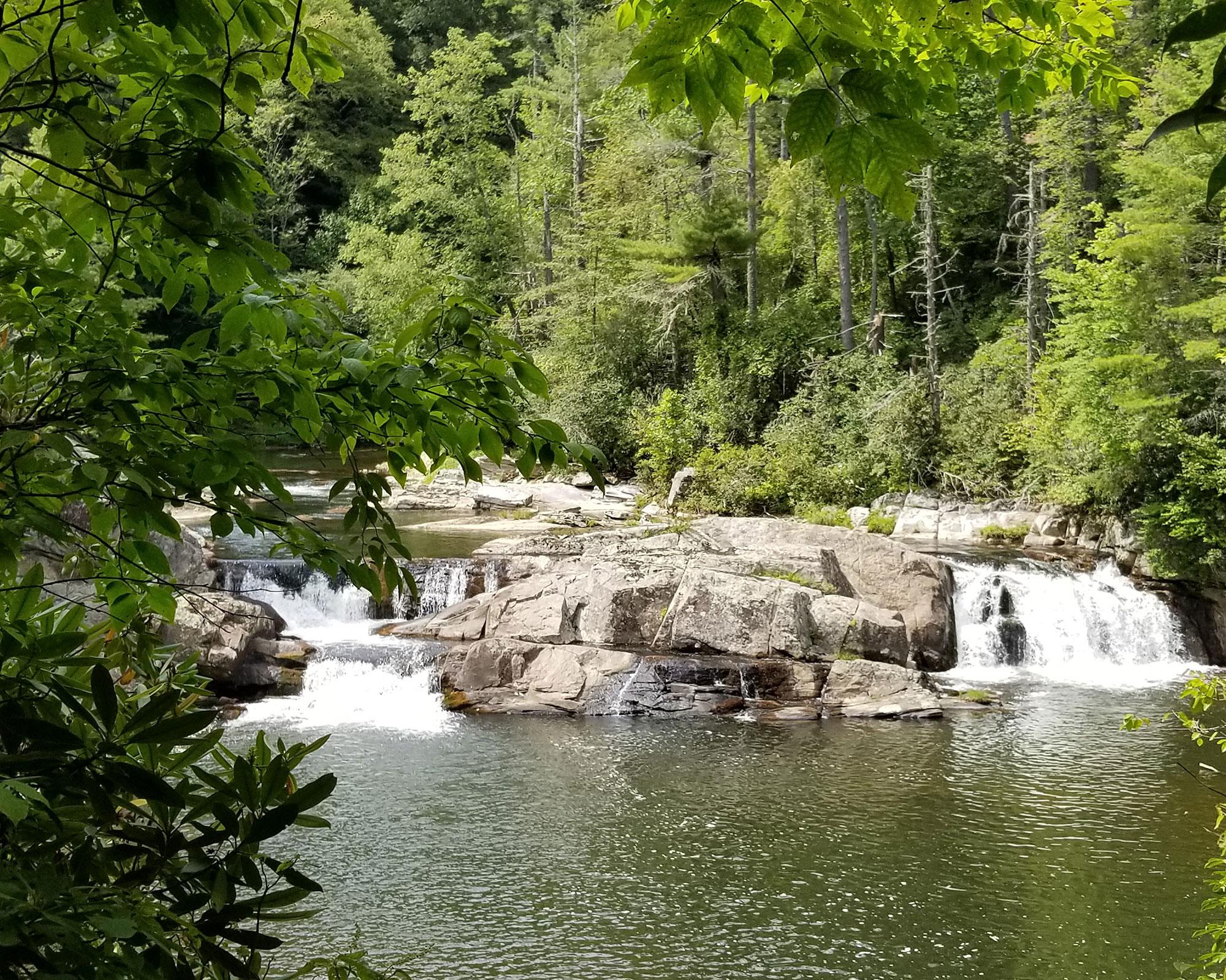 Water cascades over boulders in two small waterfalls