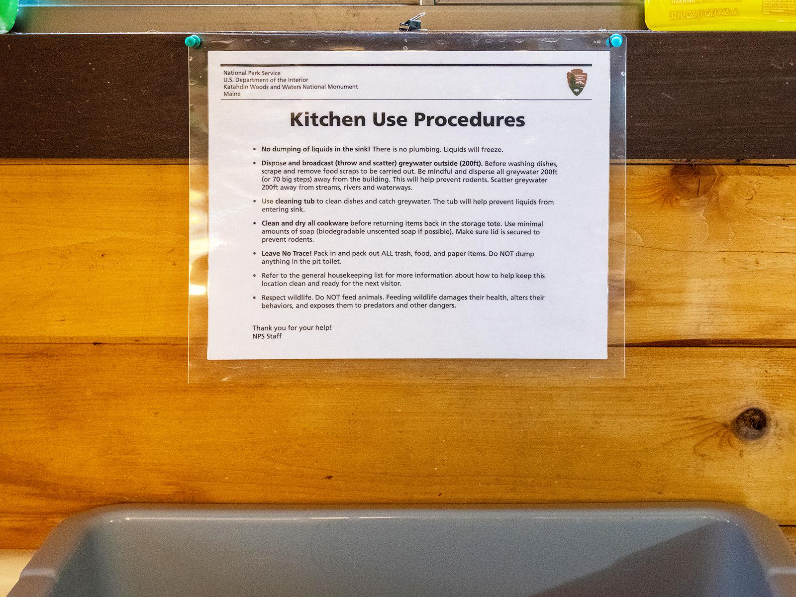 Close up of kitchen use procedures posted inside the hut with a plastic wash bin for visitor use.