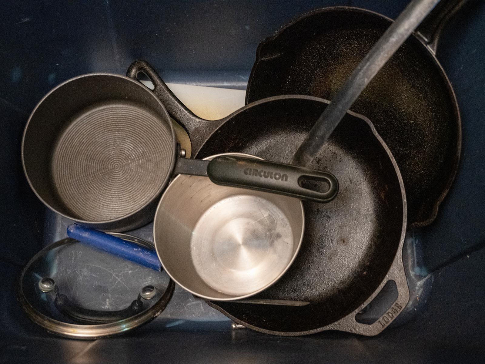 A zoomed in image of metal pots and pans in a blue tote.