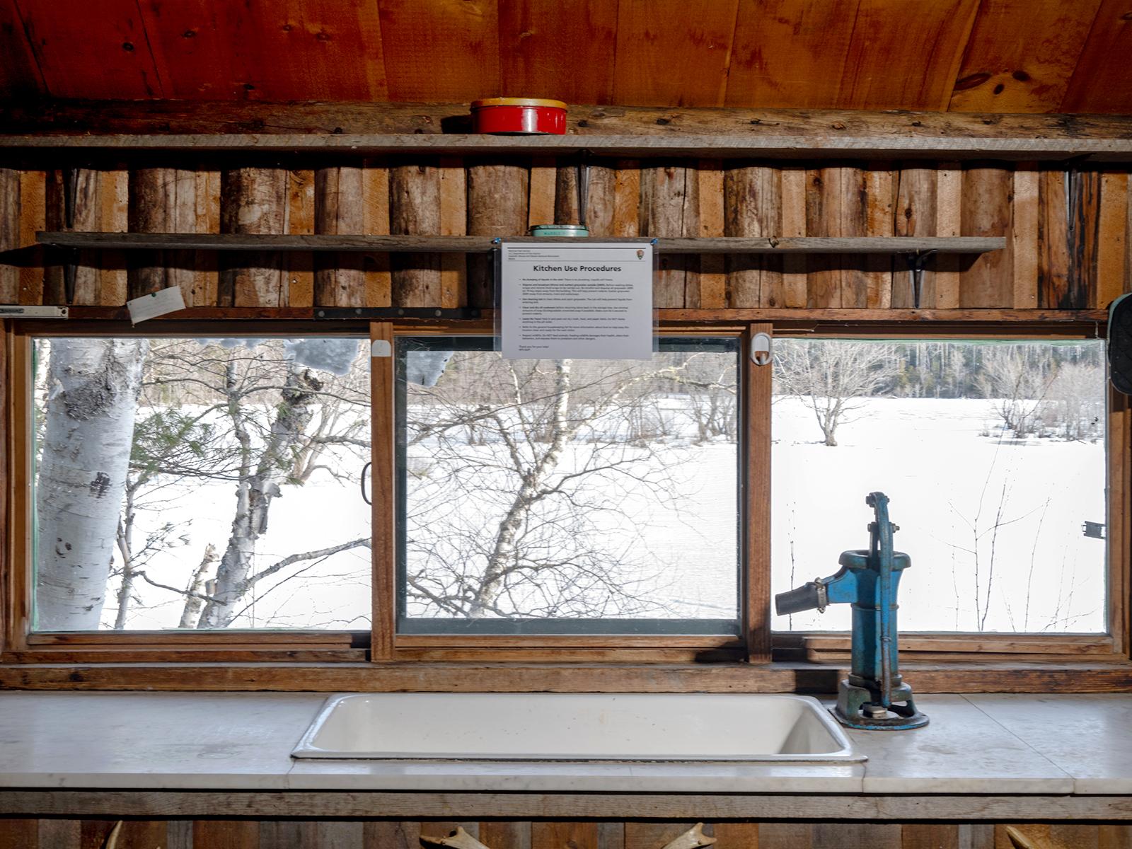 Kitchen countertop and sink with a scenic winter view outside the window.