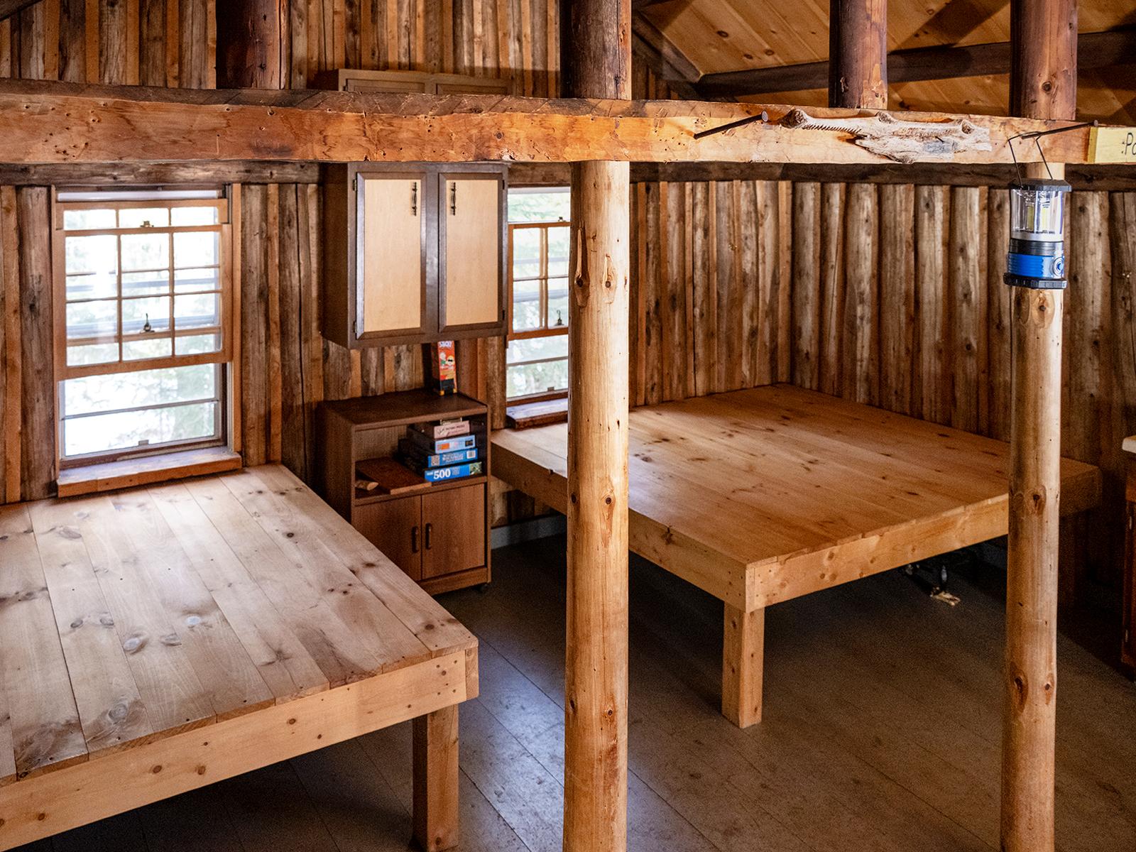 2 wooden square raised sleeping surfaces inside a log cabin