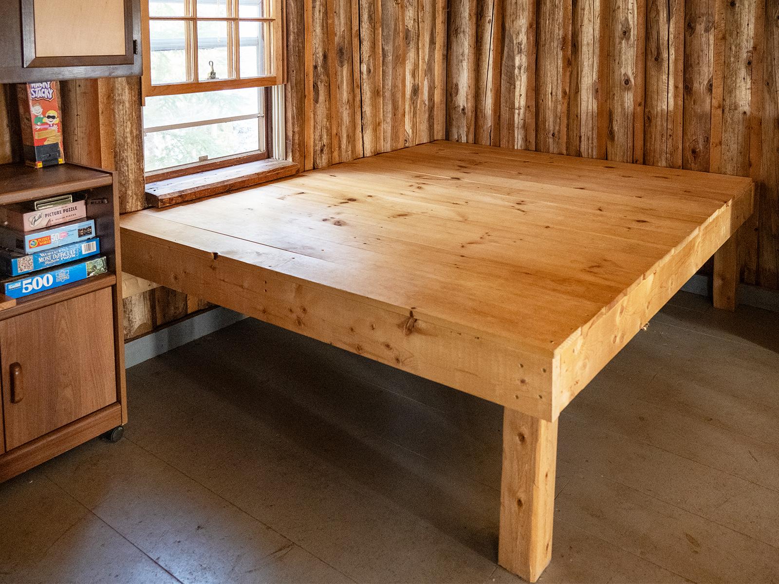 A close up of a square raised wooden platform intended for sleeping. Board games stored next to it.