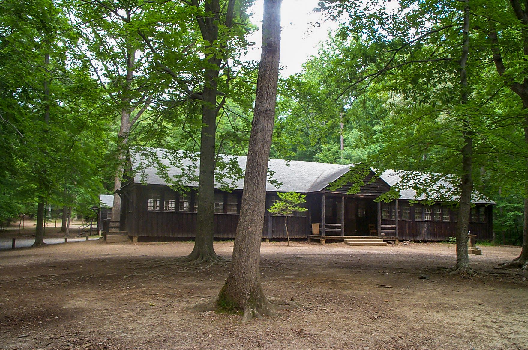 A wooden building with lots of windows sits among trees