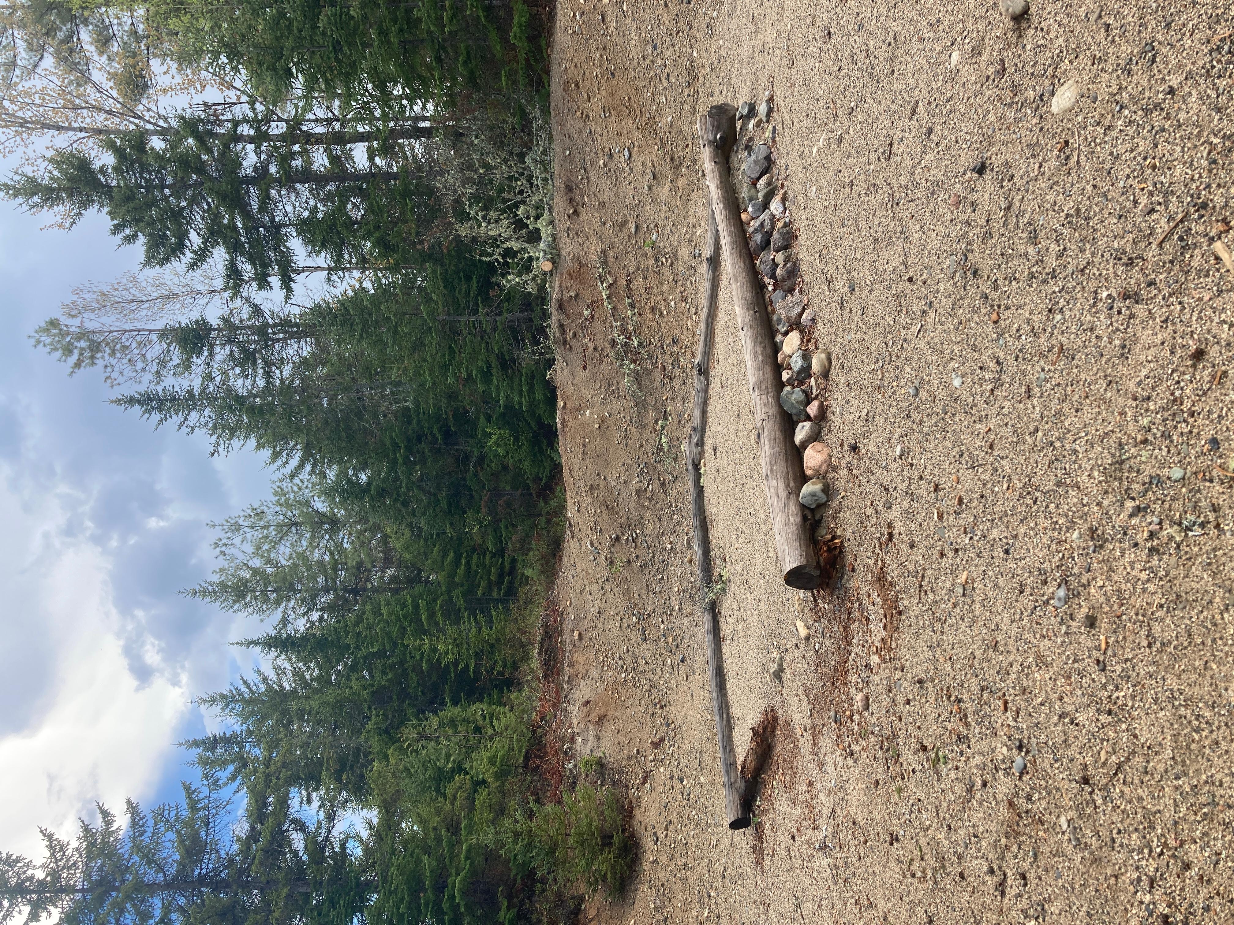 Gravel tent pad framed by logs and small rocks.
