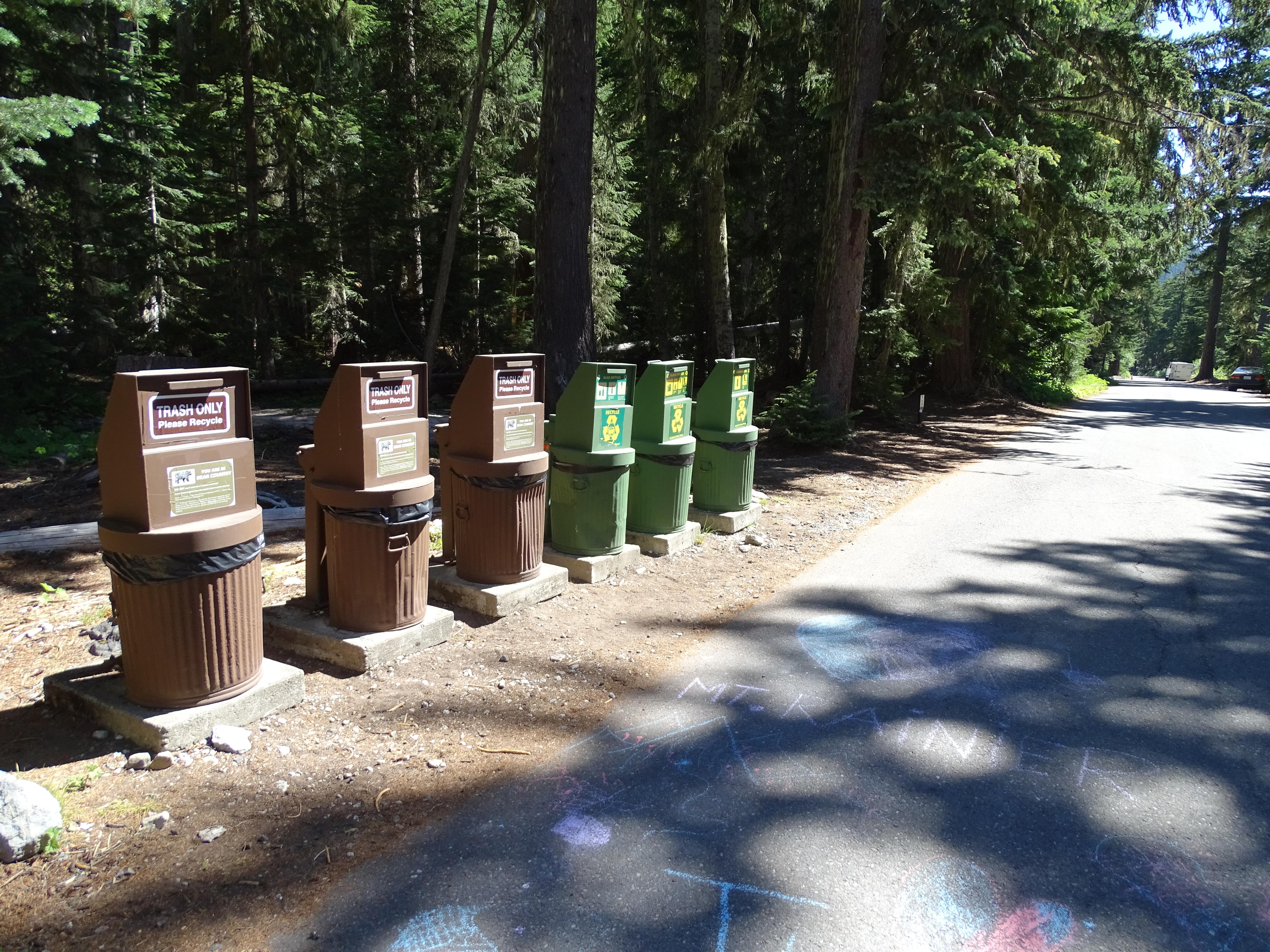 A group of six metal waste bins for trash and recycling.