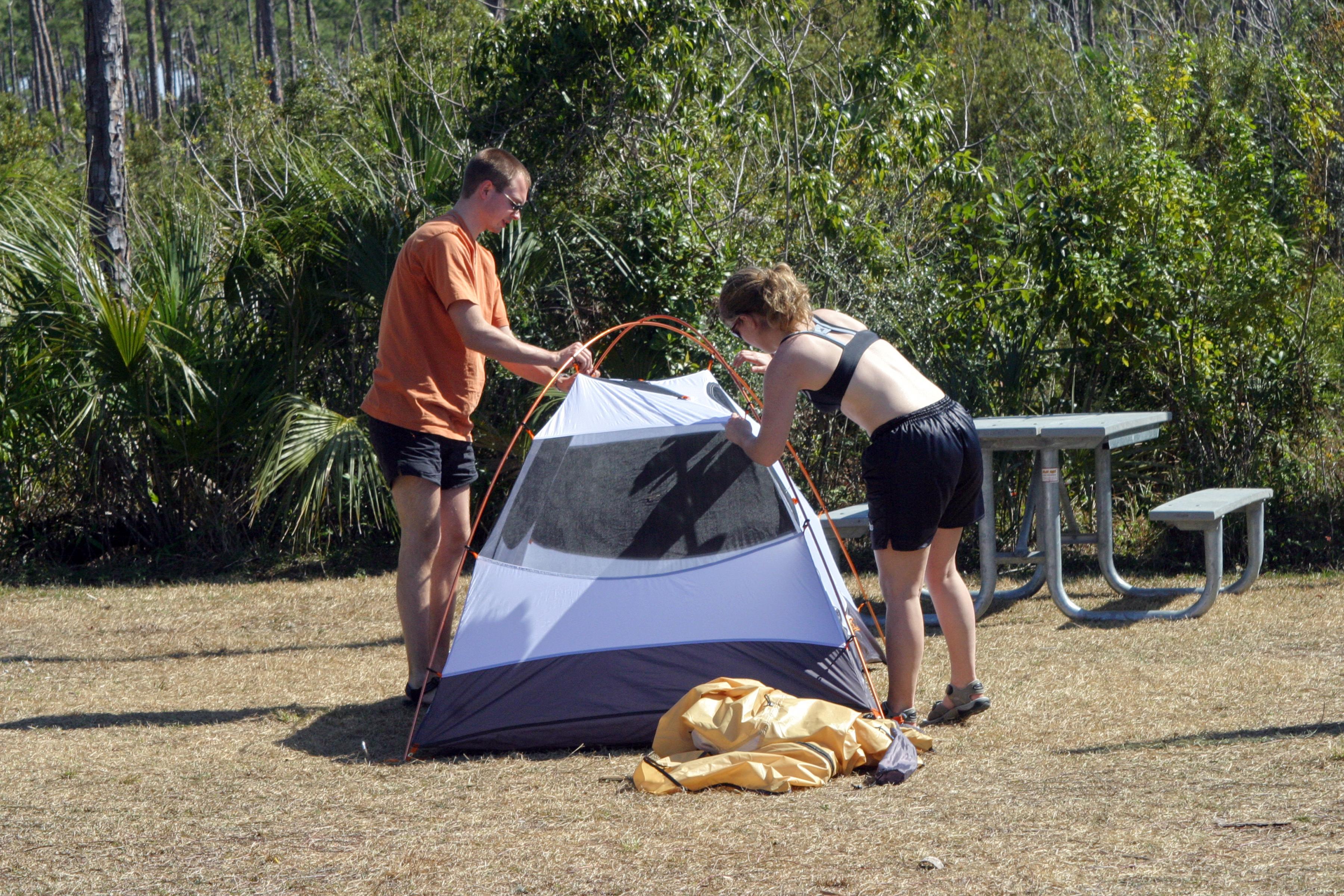 Two visitors are setting up a tent on a campsite at Long Pine Key