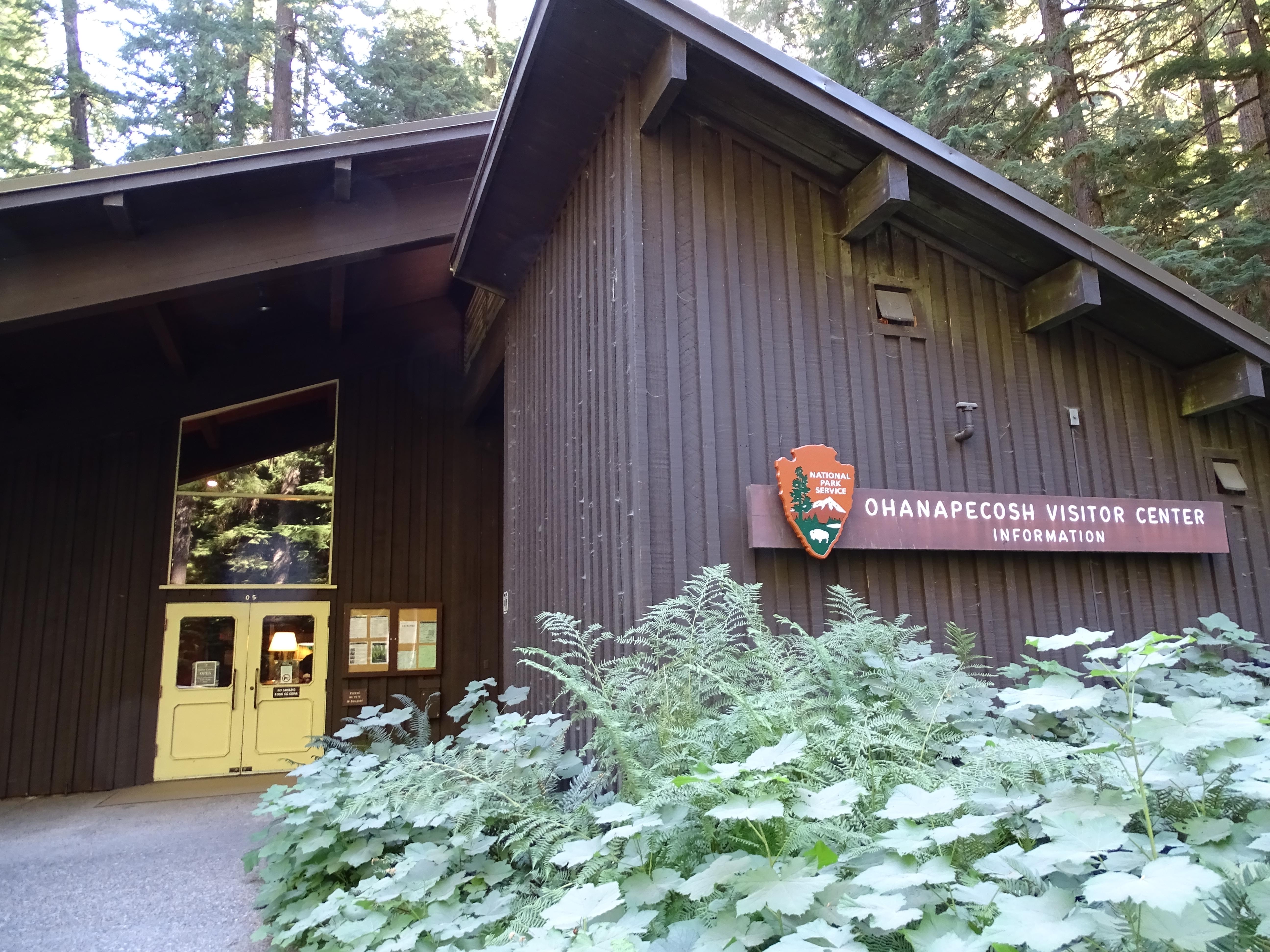 A large brown building with a slanted roof surrounded by forest.