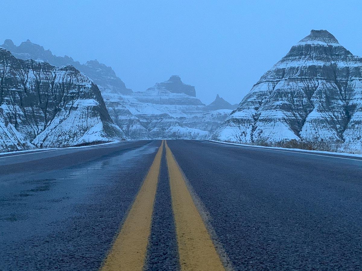 road leading between snow covered badlands formations