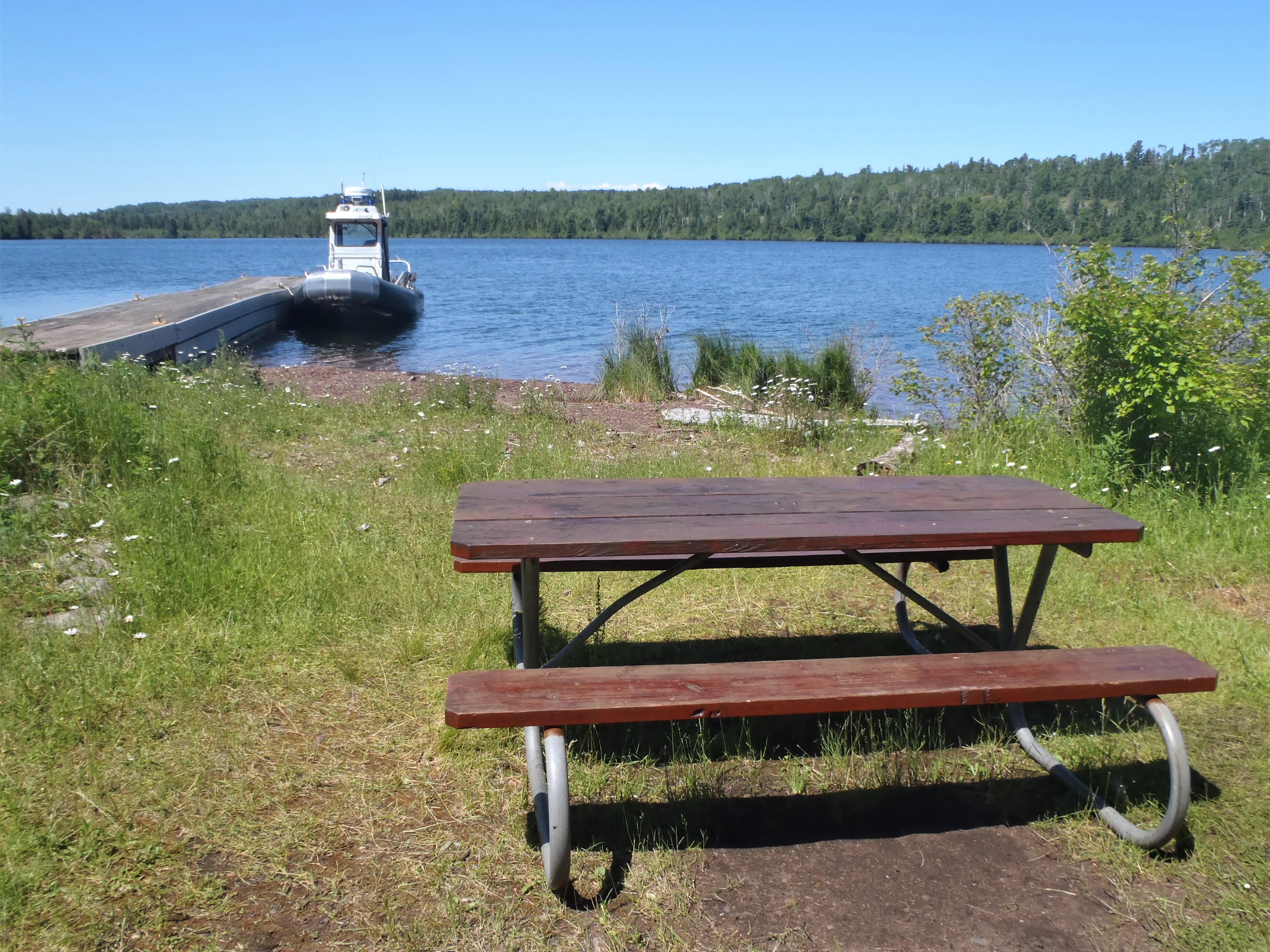 Hay Bay of Lake Superior with a boat at dock and picnic table on the foreground grassy area,