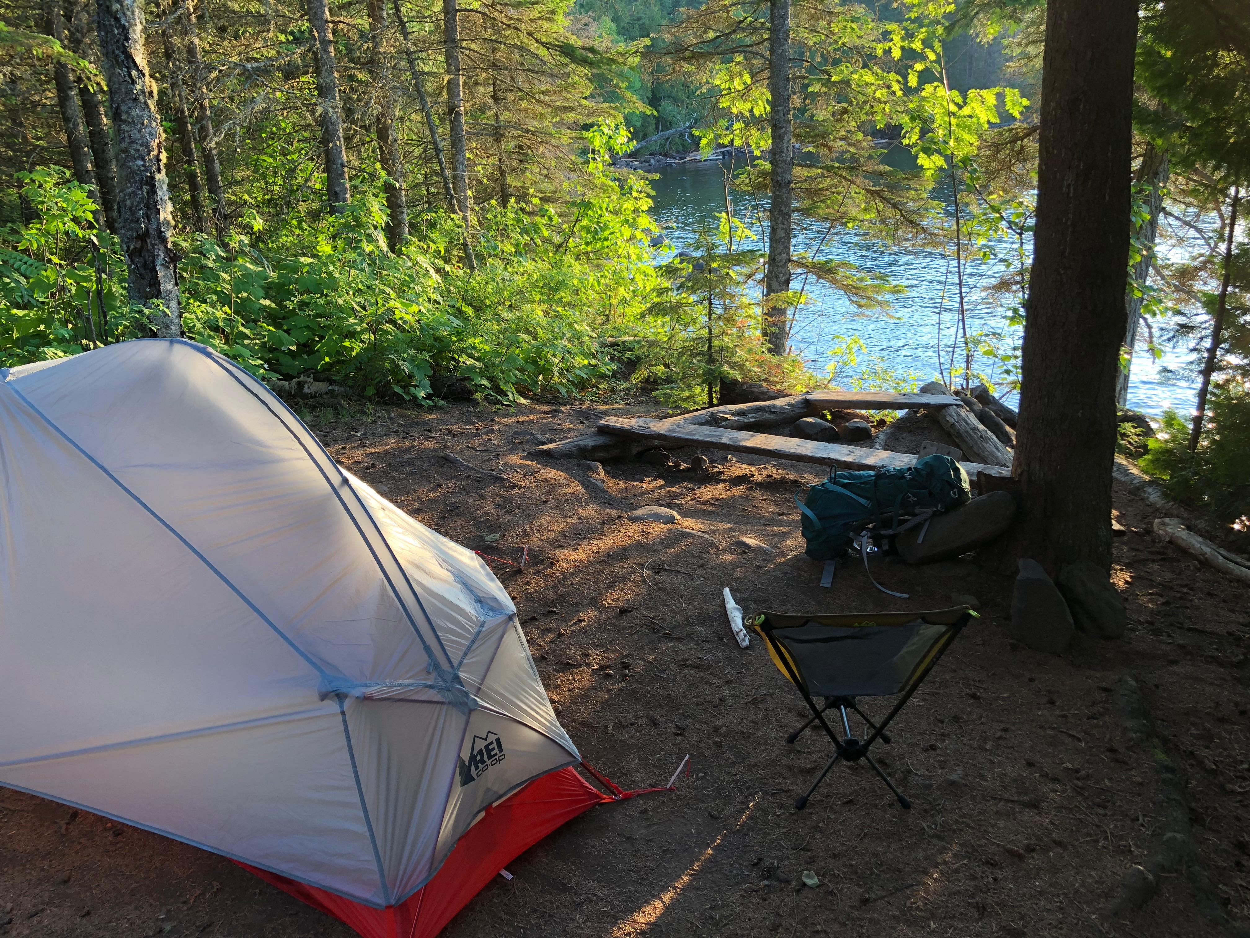 Tent and camp chair looking through tress at Huginnin Cove of Lake Superior.