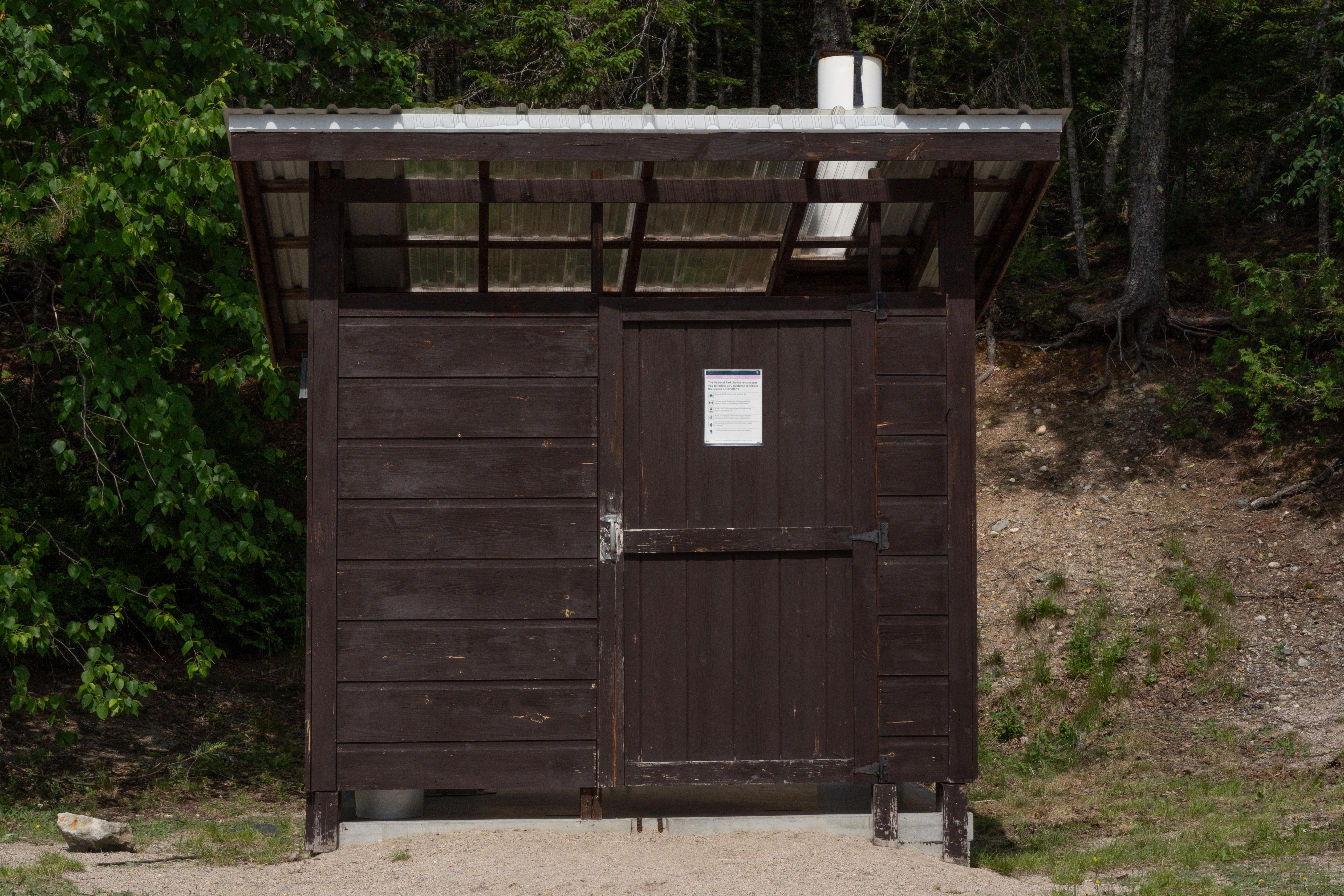 Pit toilet on concrete pad.