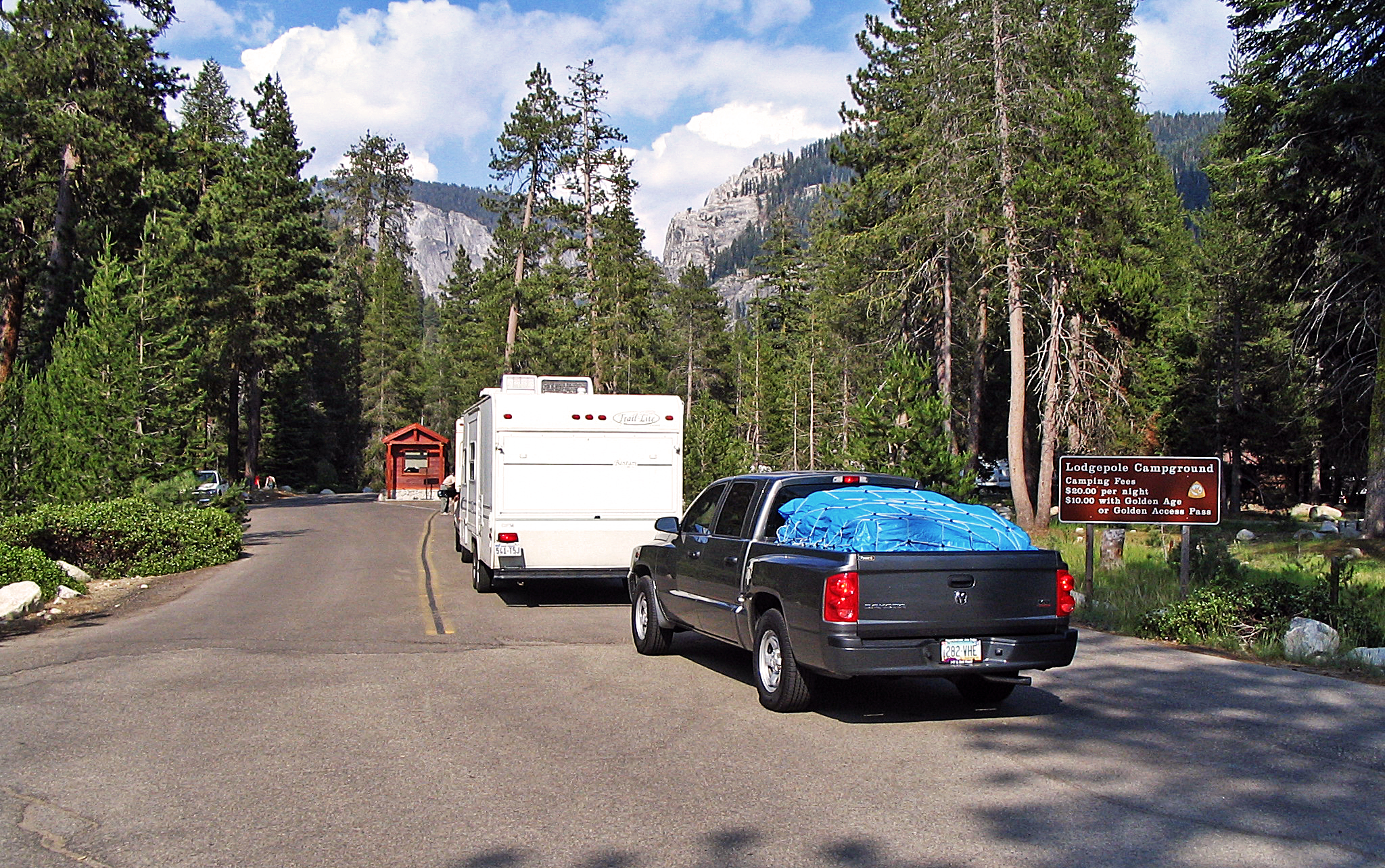 Vehicles near a kiosk in a forested canyon