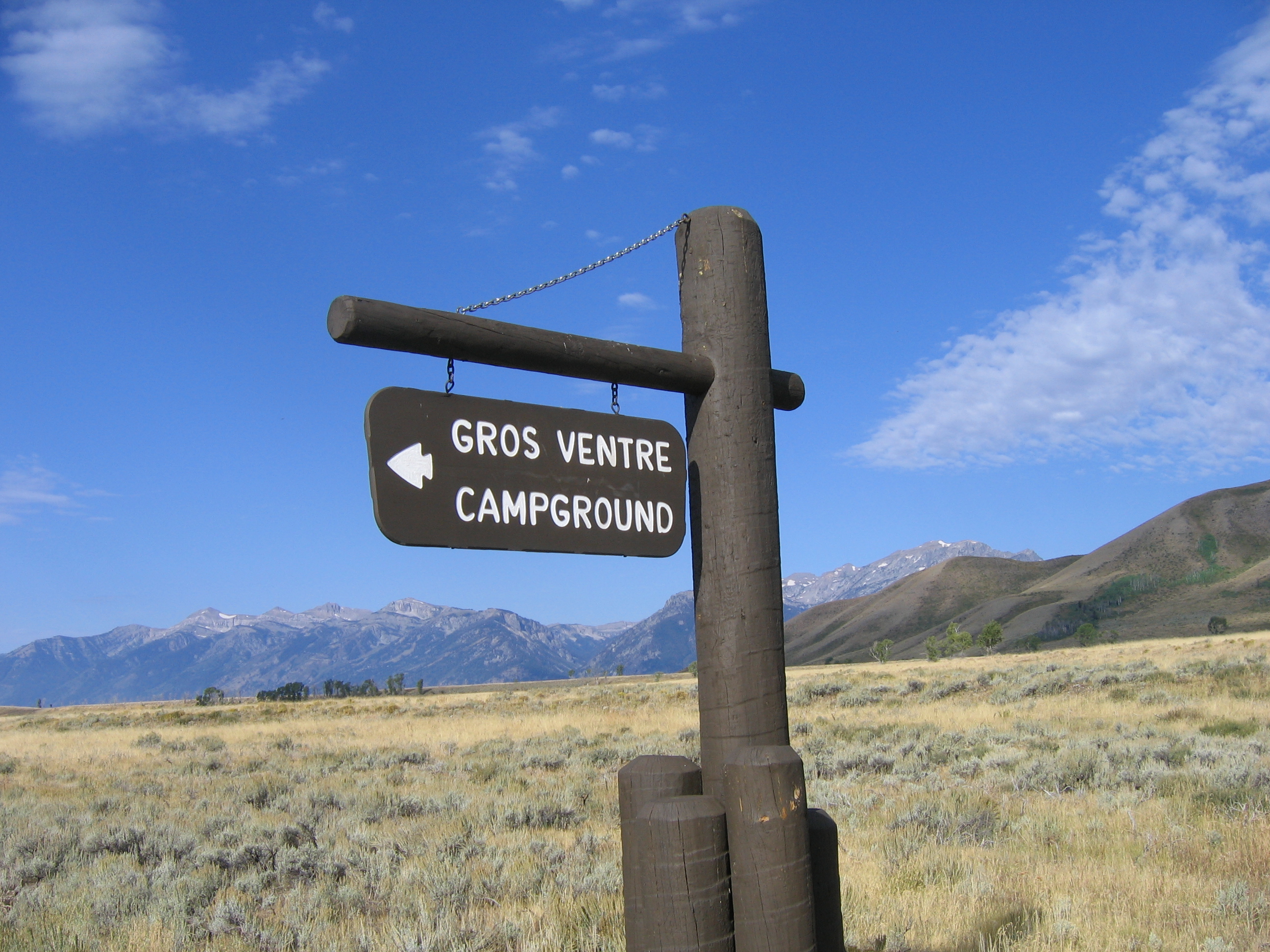 Entrance sign for Gros Ventre Campground with Blacktail Butte and the Teton Range in the distance.