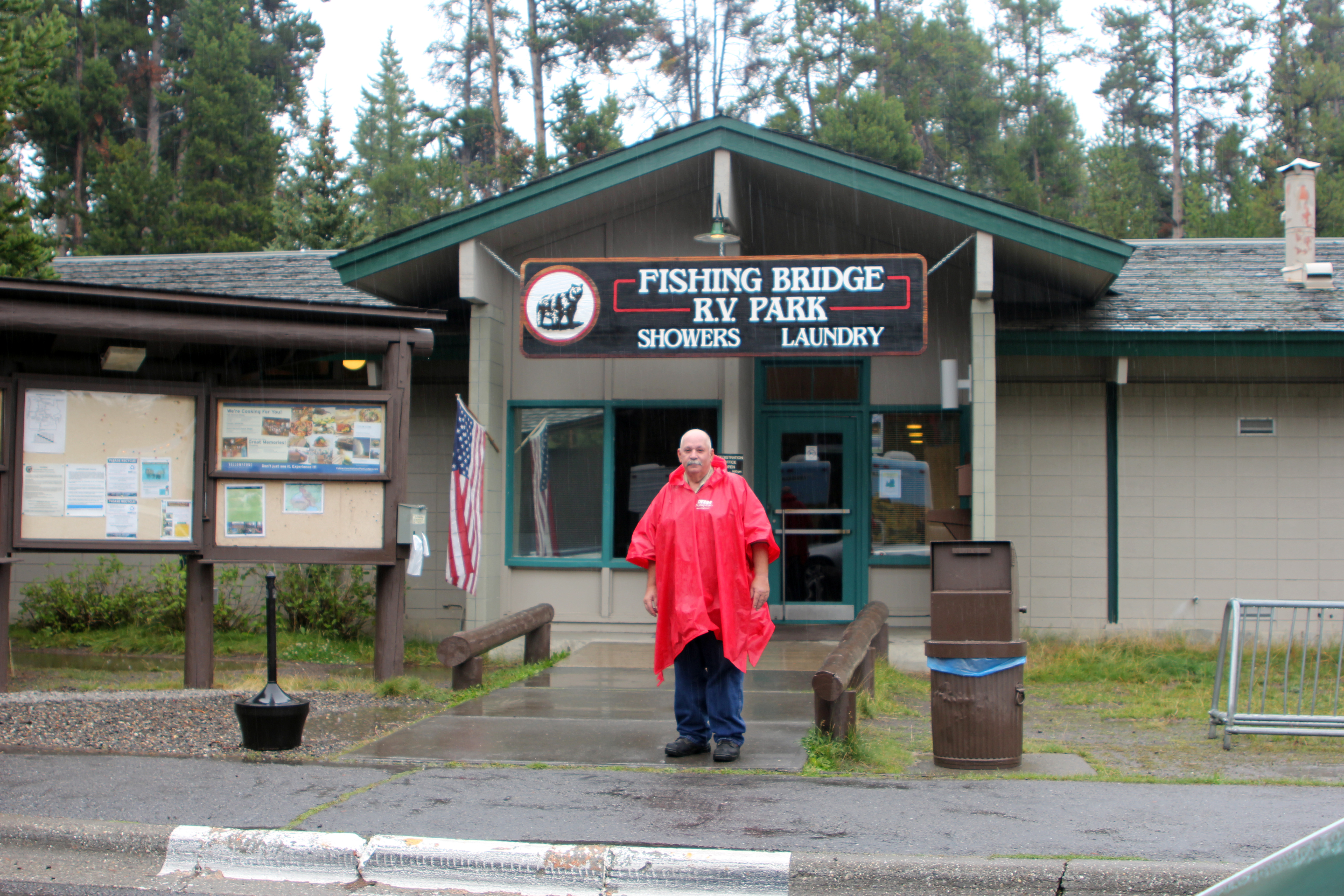Man dressed inraincoat standing in front of building.