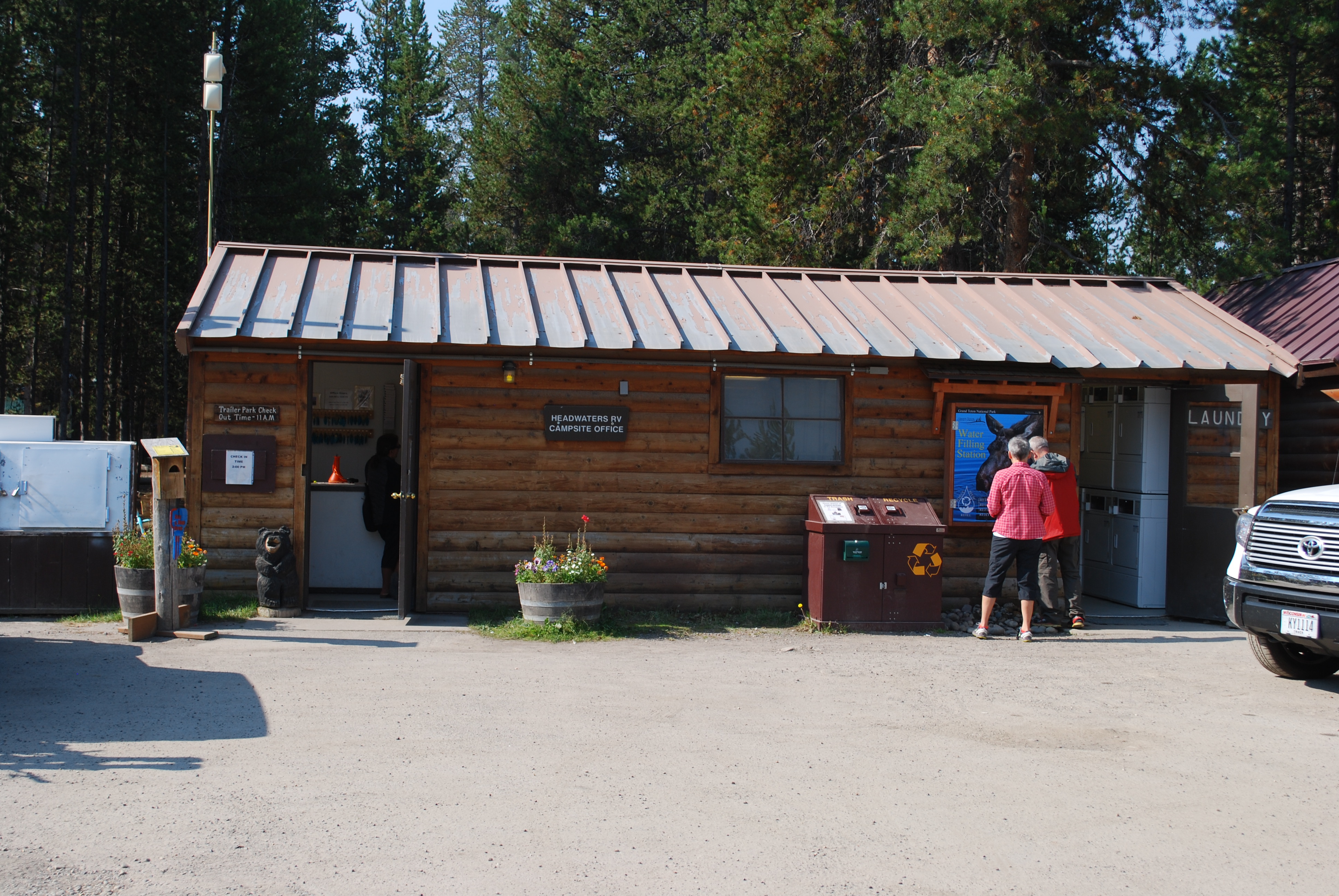 small wooden office building with visitor in front and car to the side.