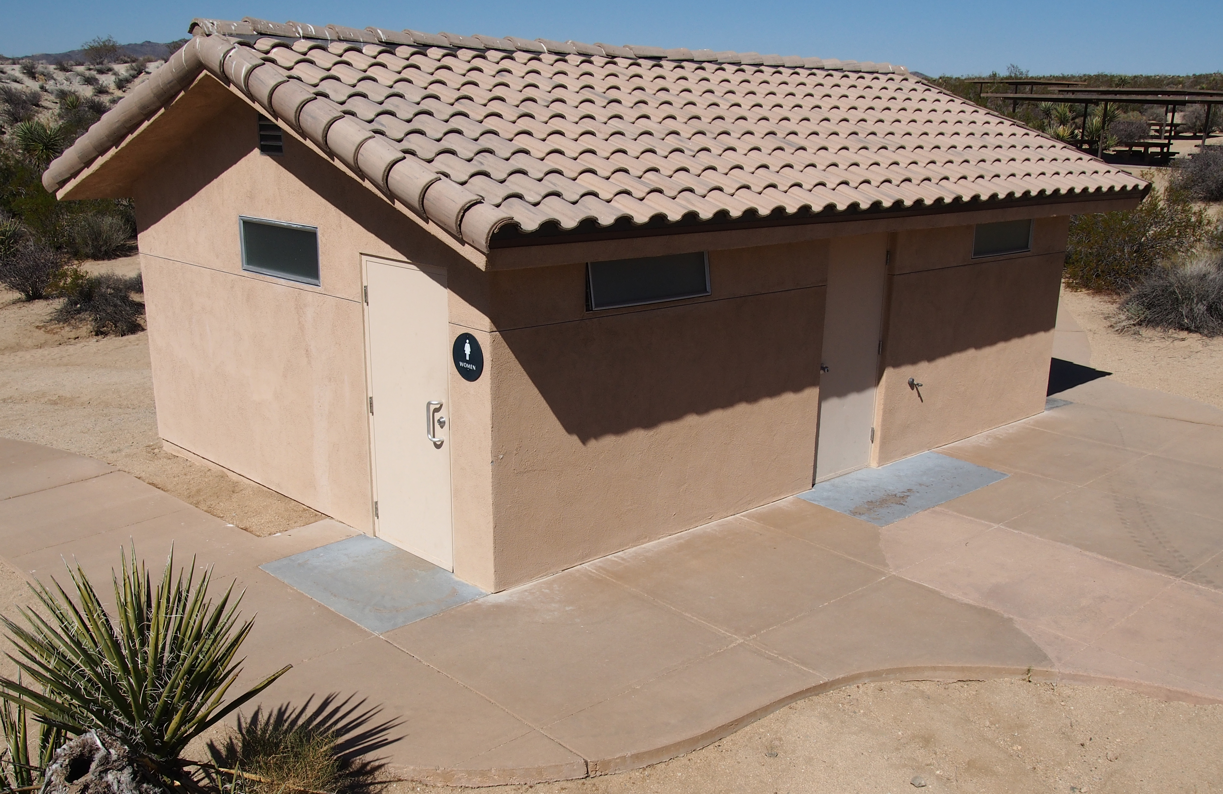 A small building with two doors and a circular sign that says "women"