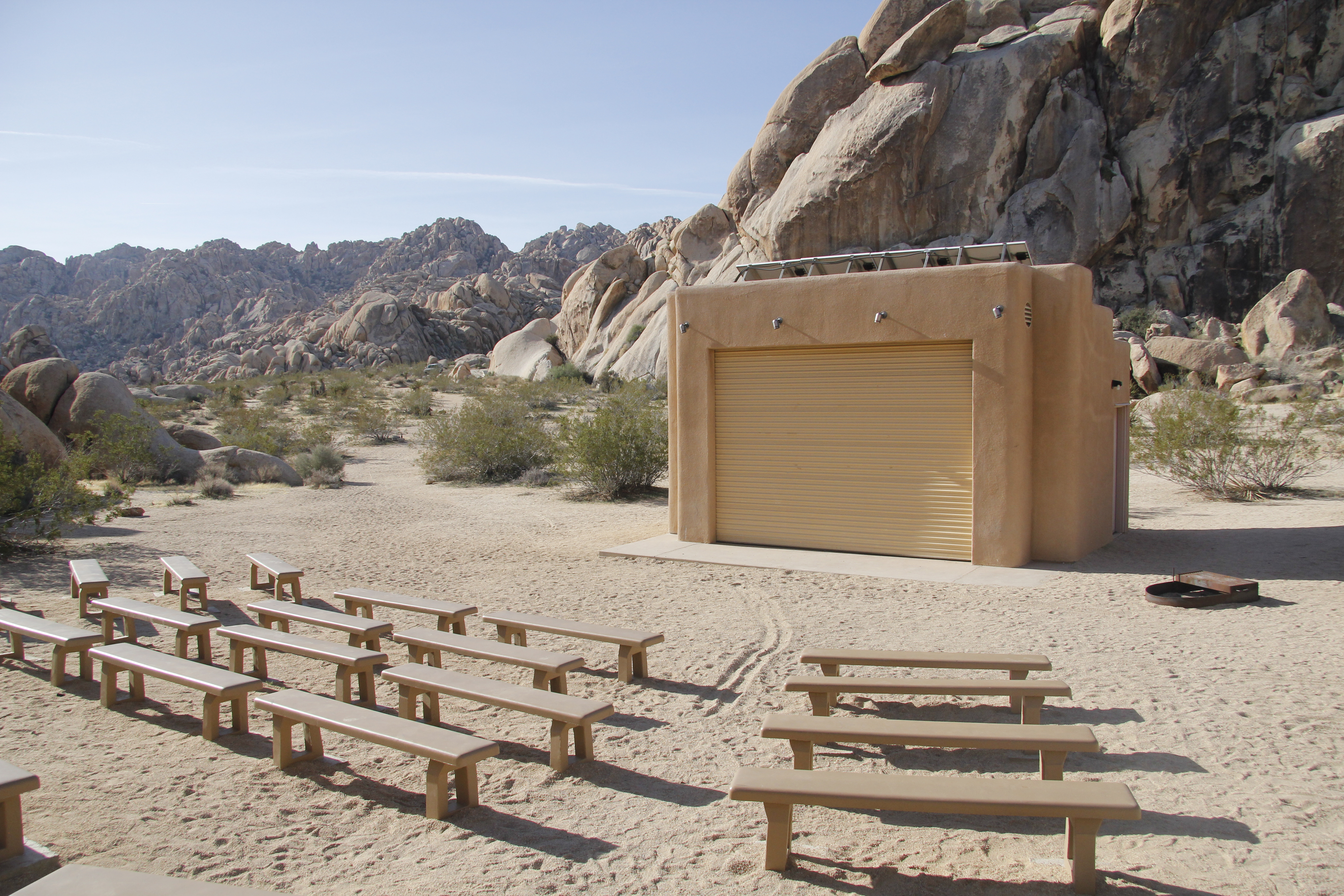 Rows of seats and a stage surrounded by a large rock formation.