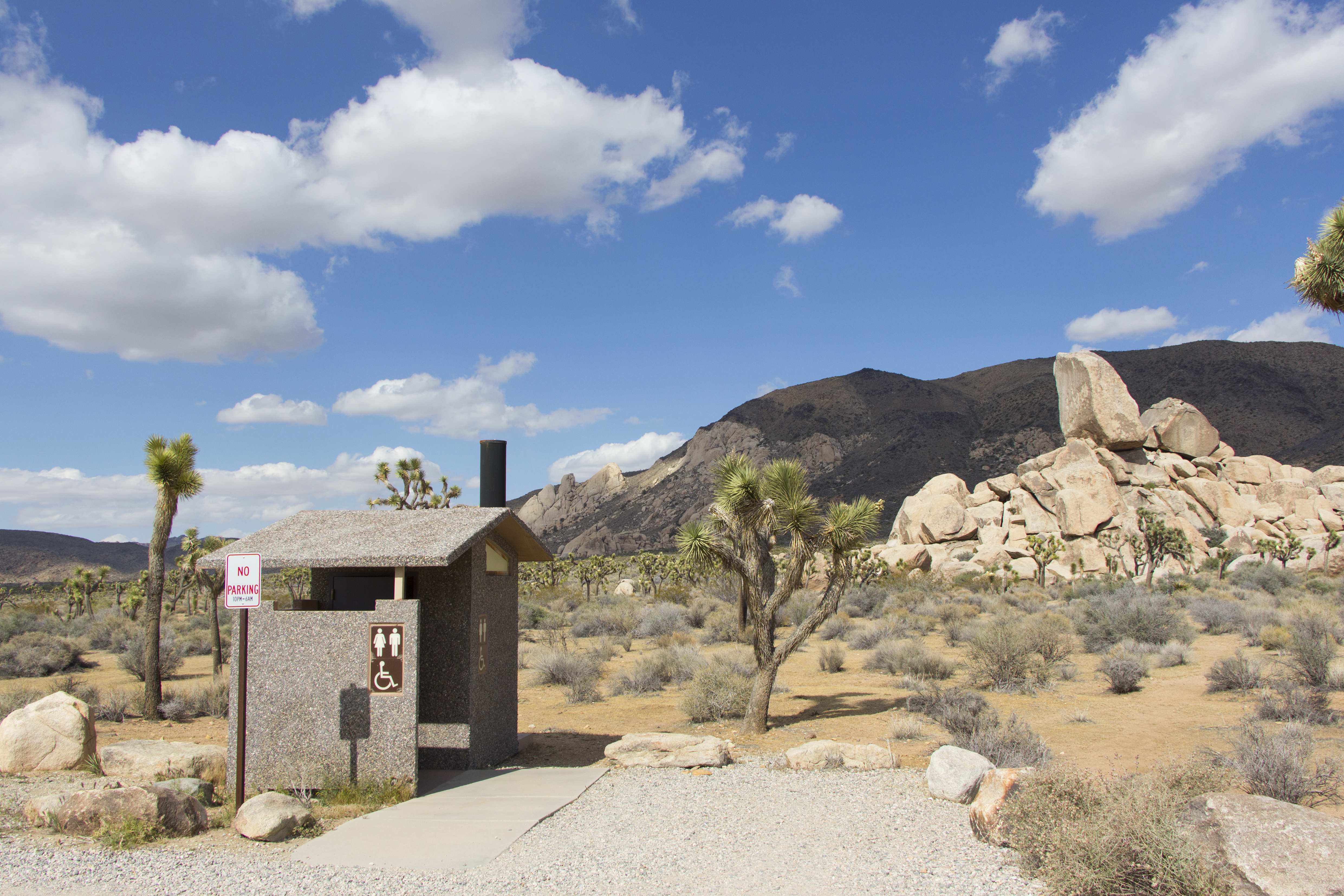 A small wheel chair accessible vault toilet and parking space.