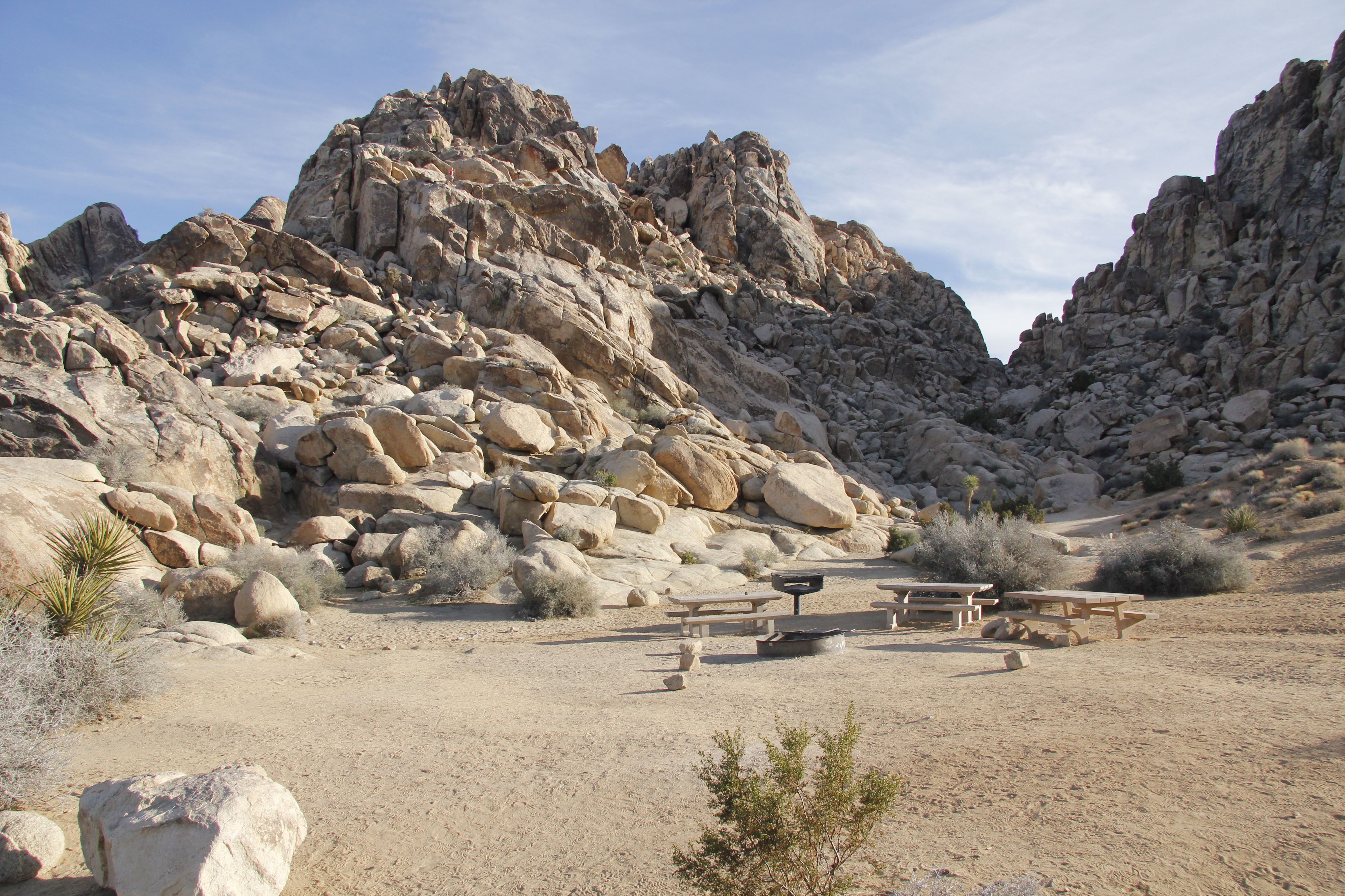A campsite with picnic tables and surrounded by large rocky formations.