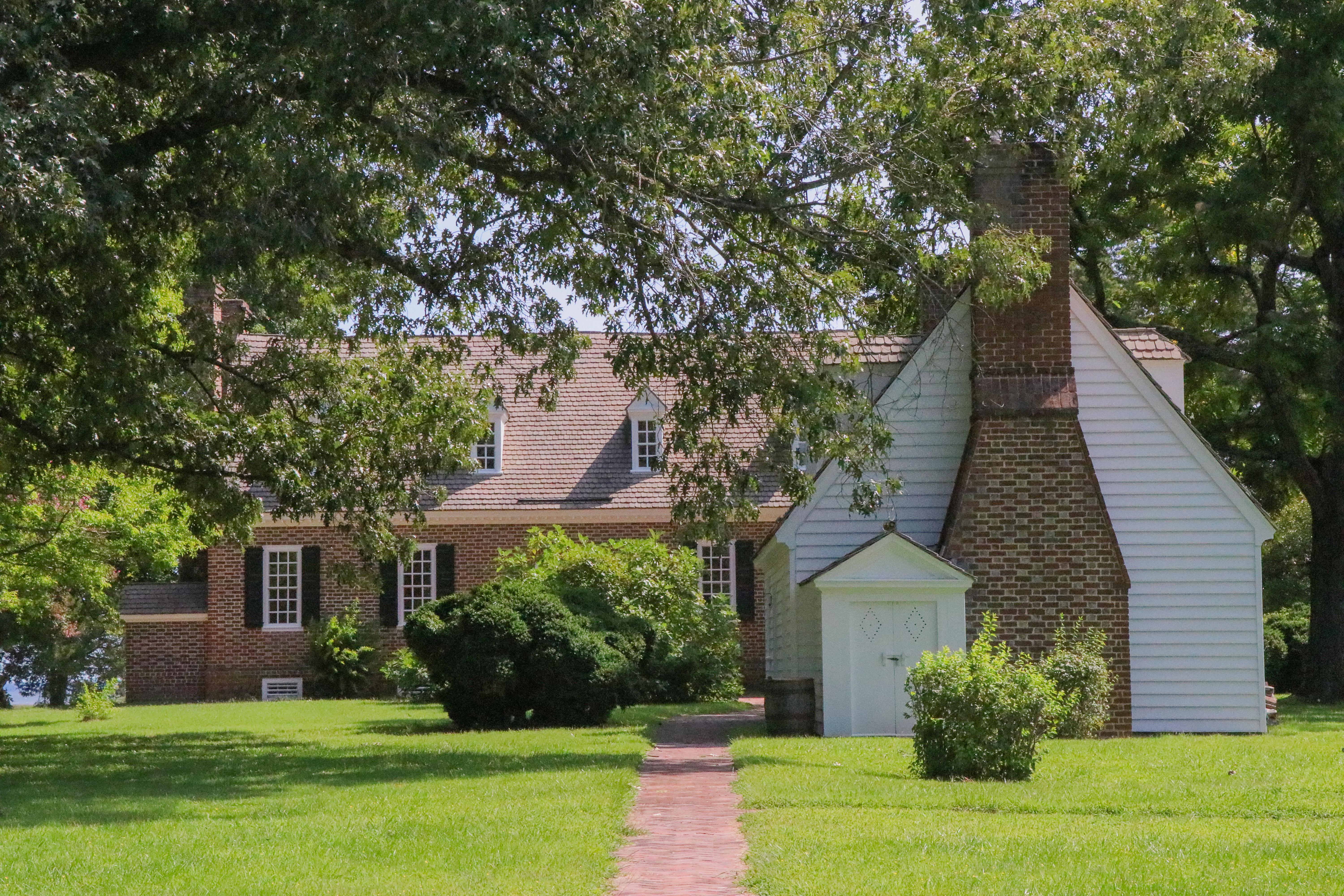 Two buildings surrounded by green foliage with a brick path leading to the buildings.