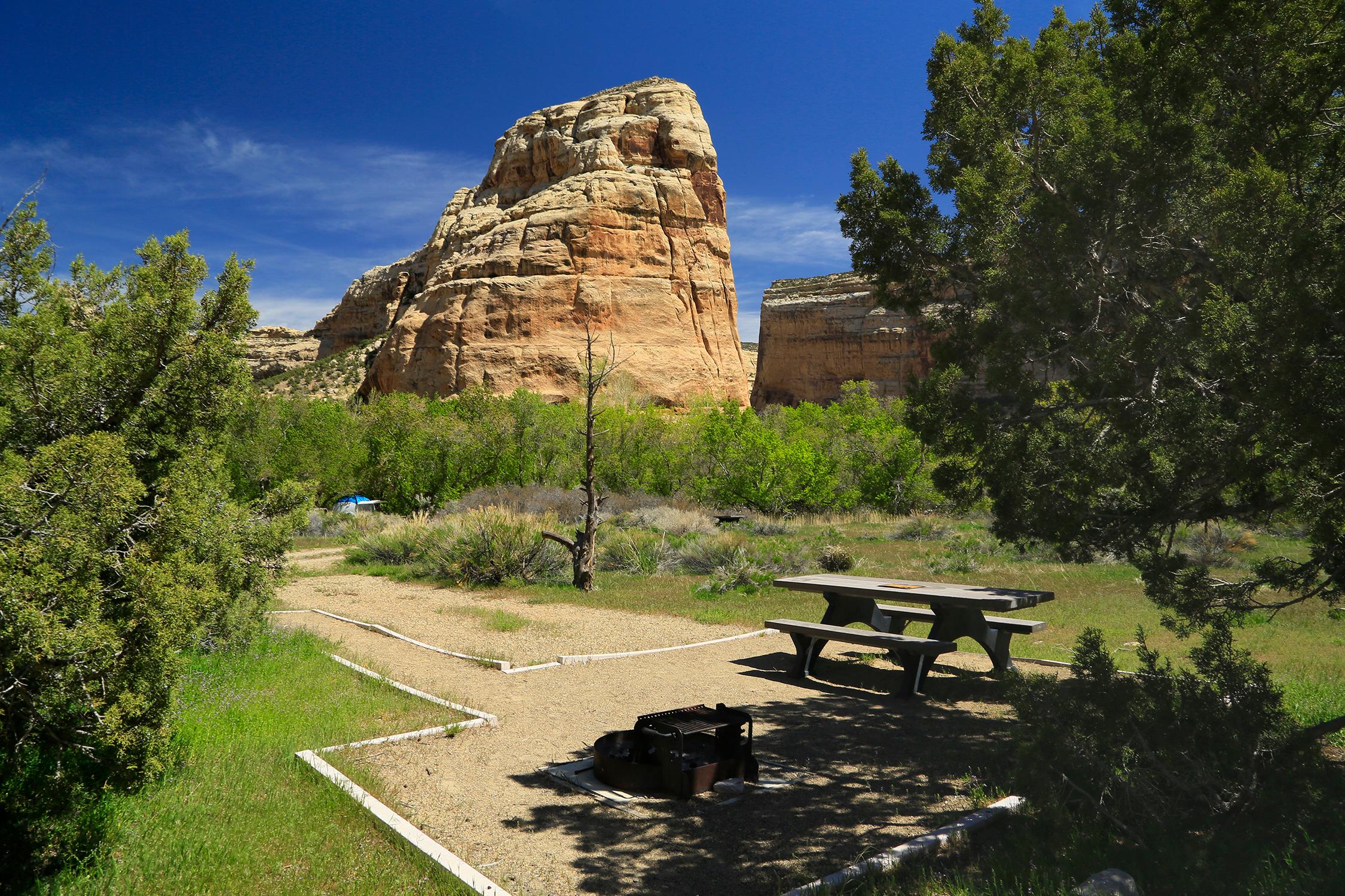 Campsite with picnic table and rock spire in the background.