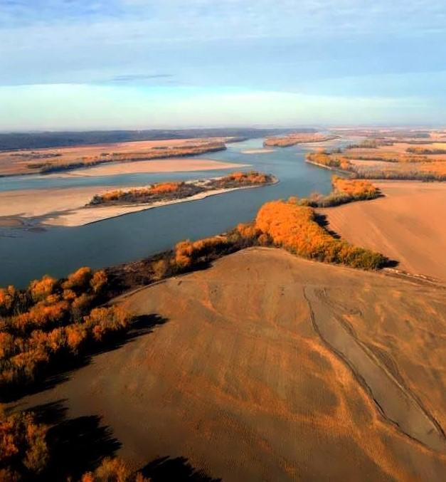 Aerial view of Goat Island in the fall at sunset. Burnt orange leafed trees and blue sky with clouds