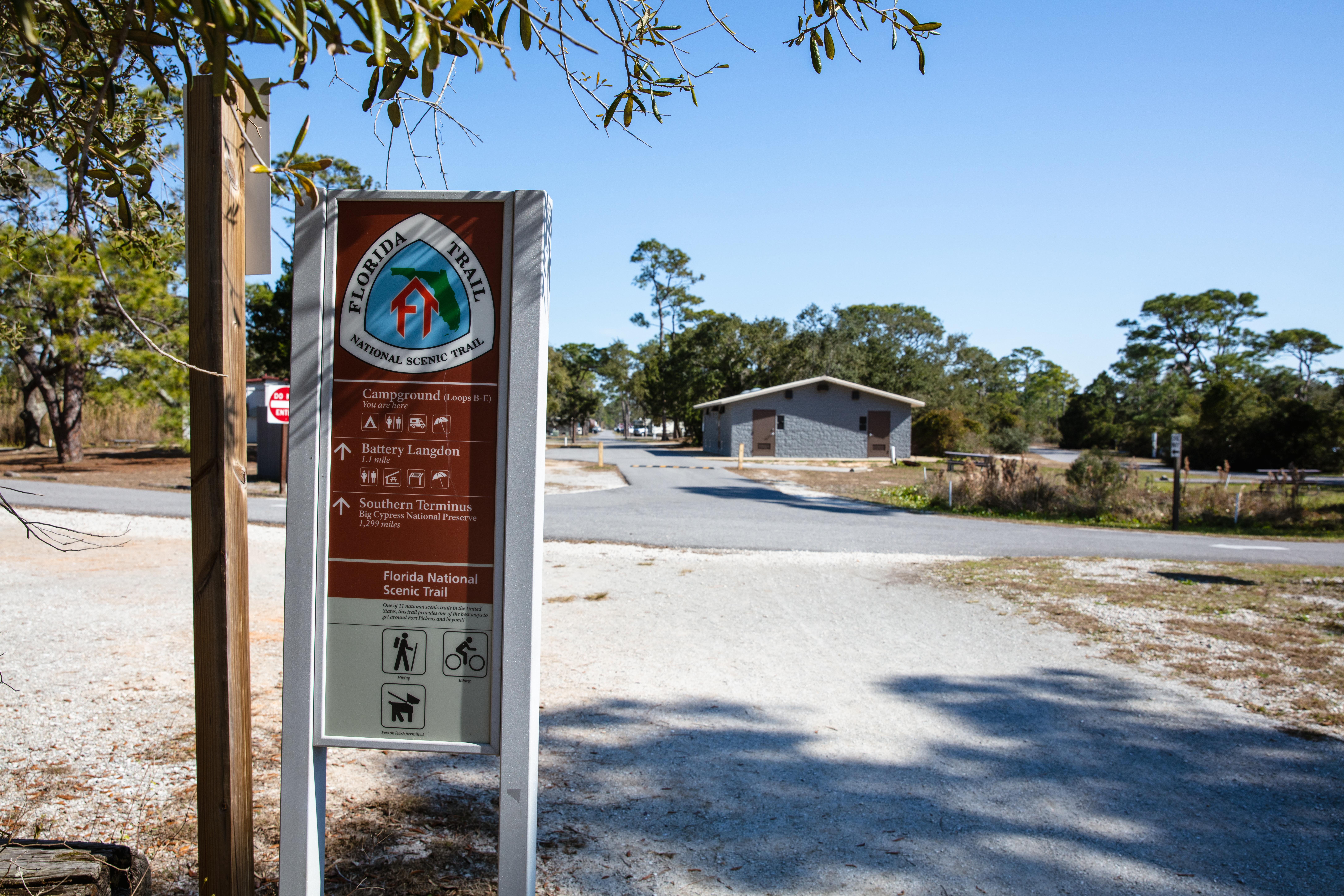 A sign for the Florida National Scenic Trail stands in front of a campground loop.