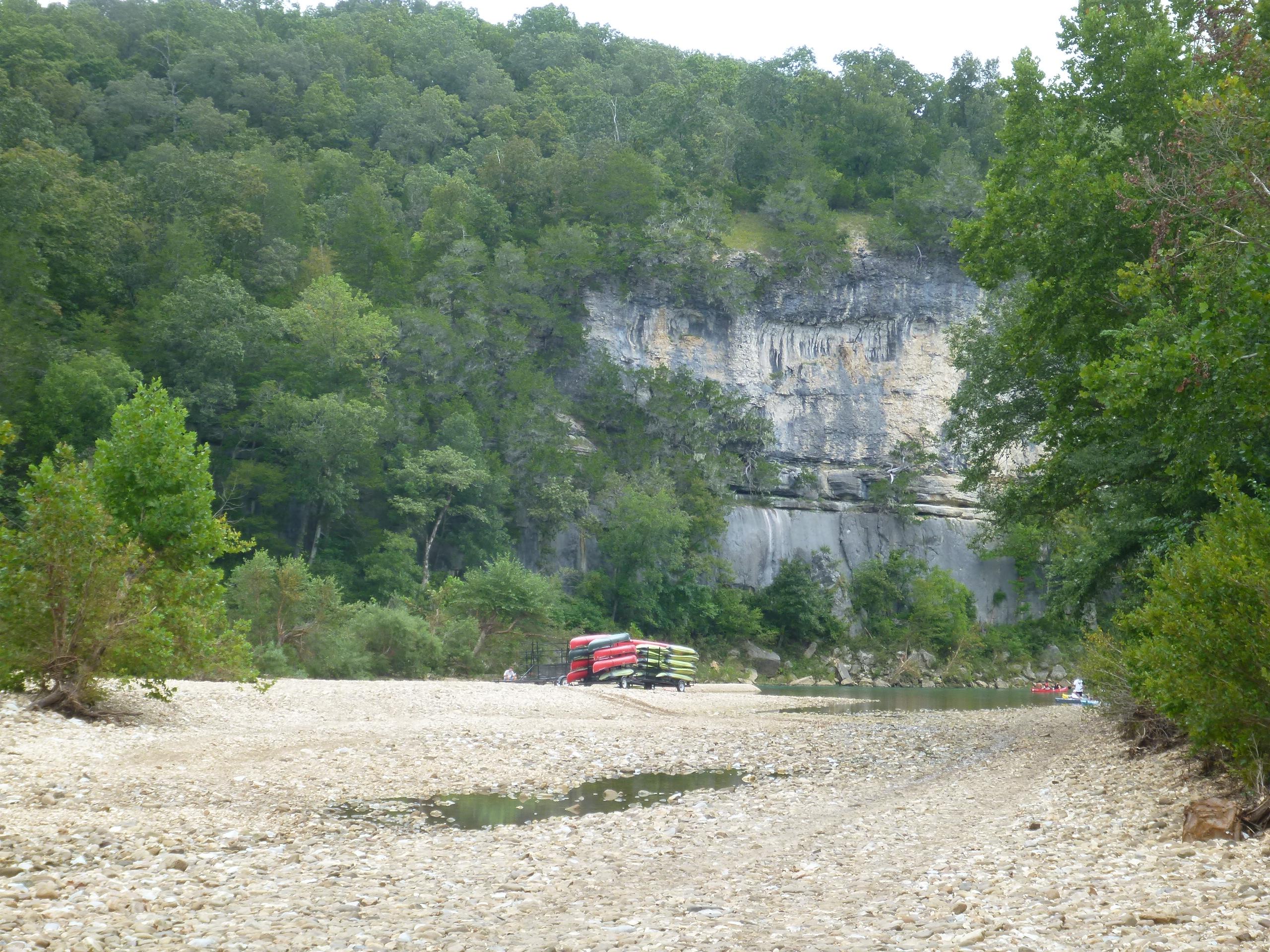 Bluff with the river, gravel bar, and a canoe trailer in foreground.