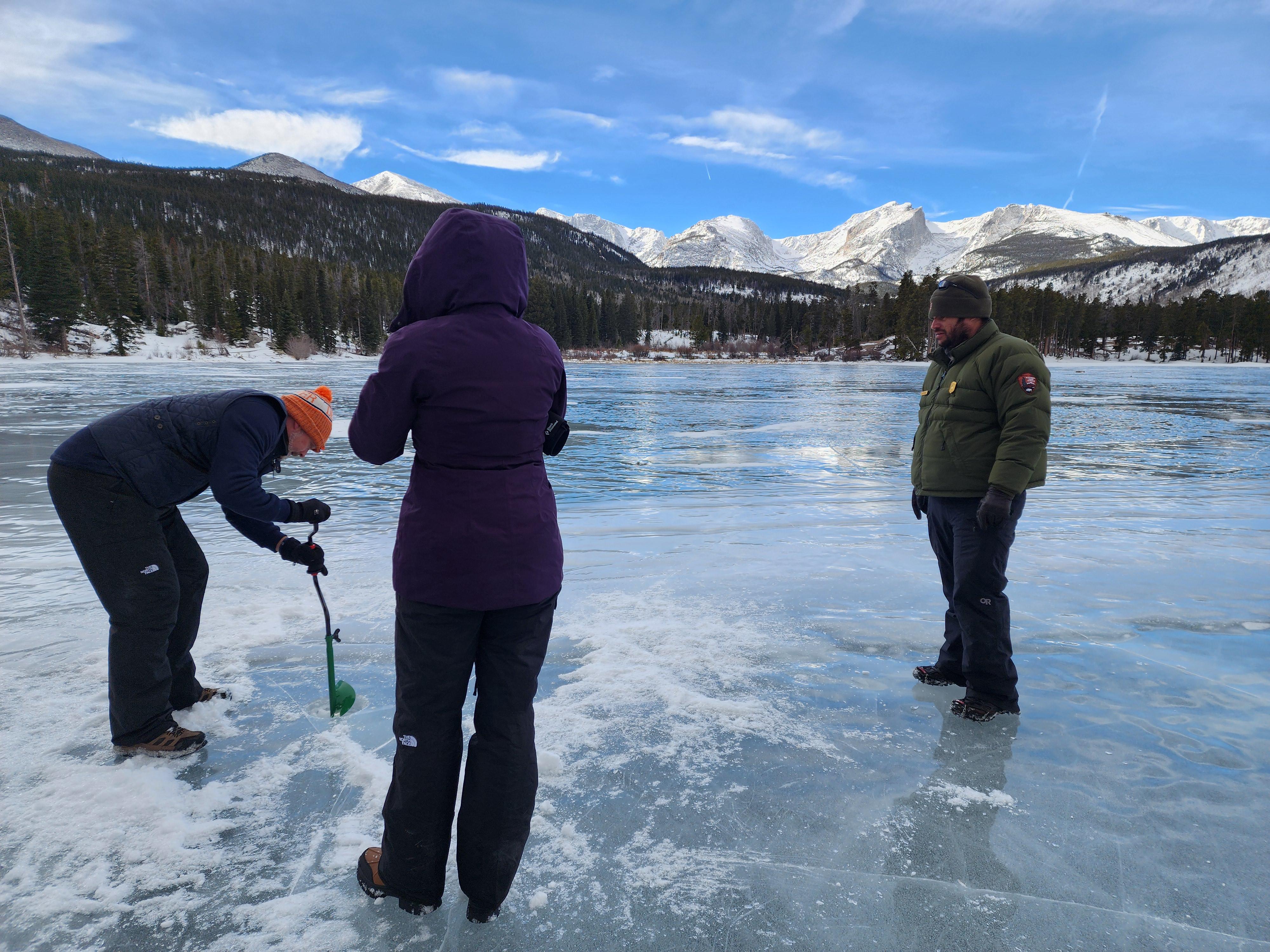 Park visitors are drilling a hole in ice for ice fishing