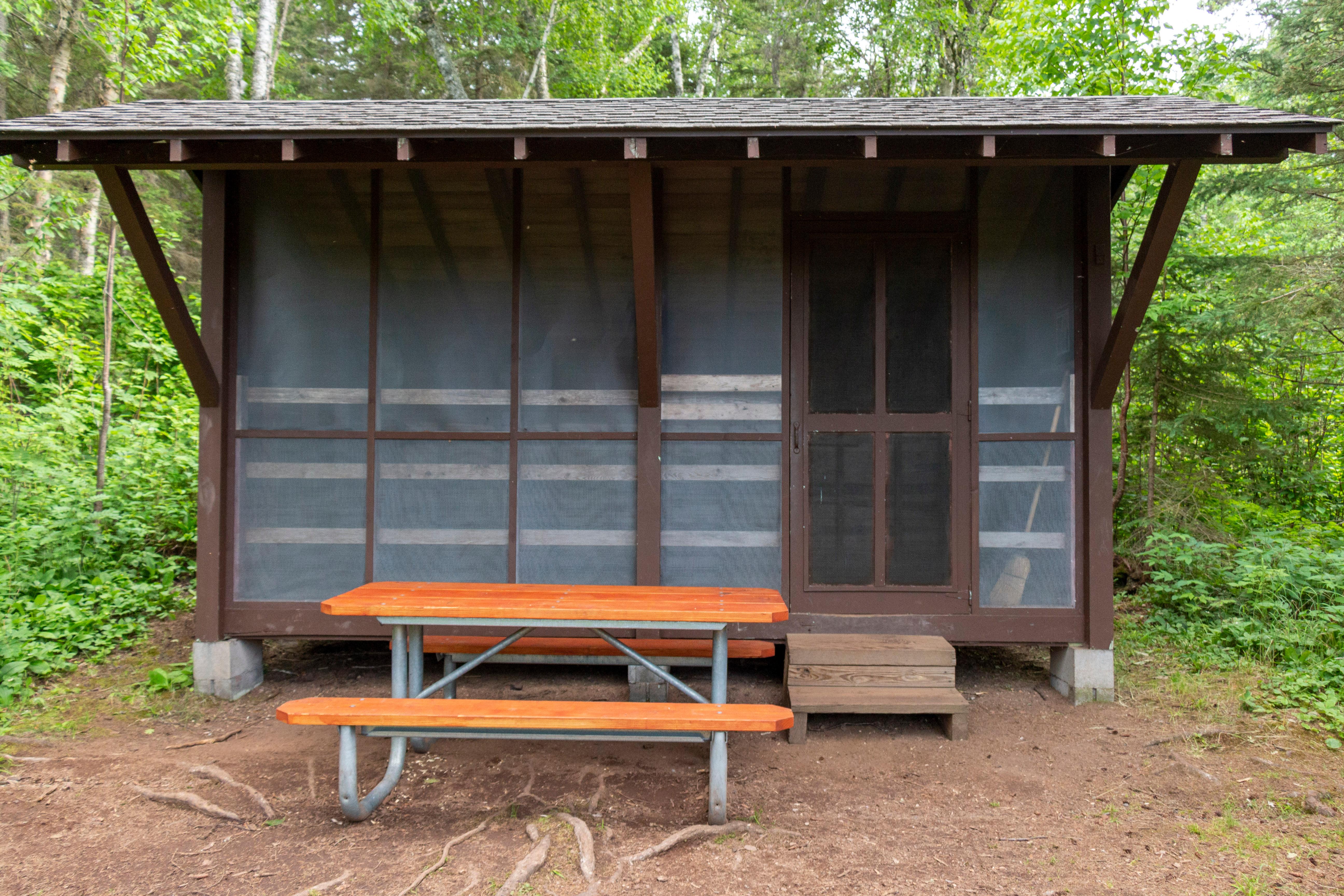 Wooden shelter for camping with a picnic table.