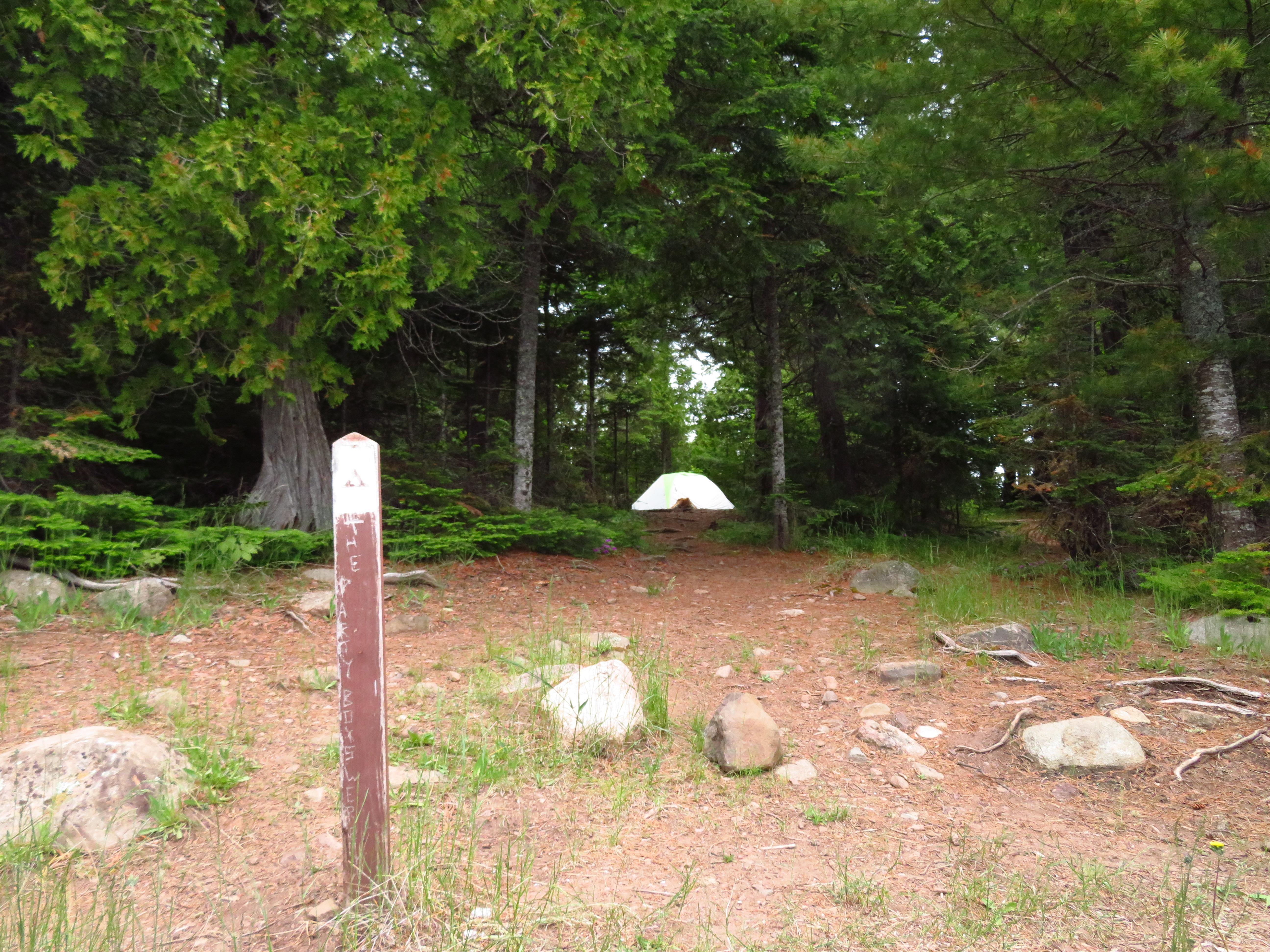 Lake Richie Canoe Campsite with sign post in foreground, tent surrounded by trees in distance.
