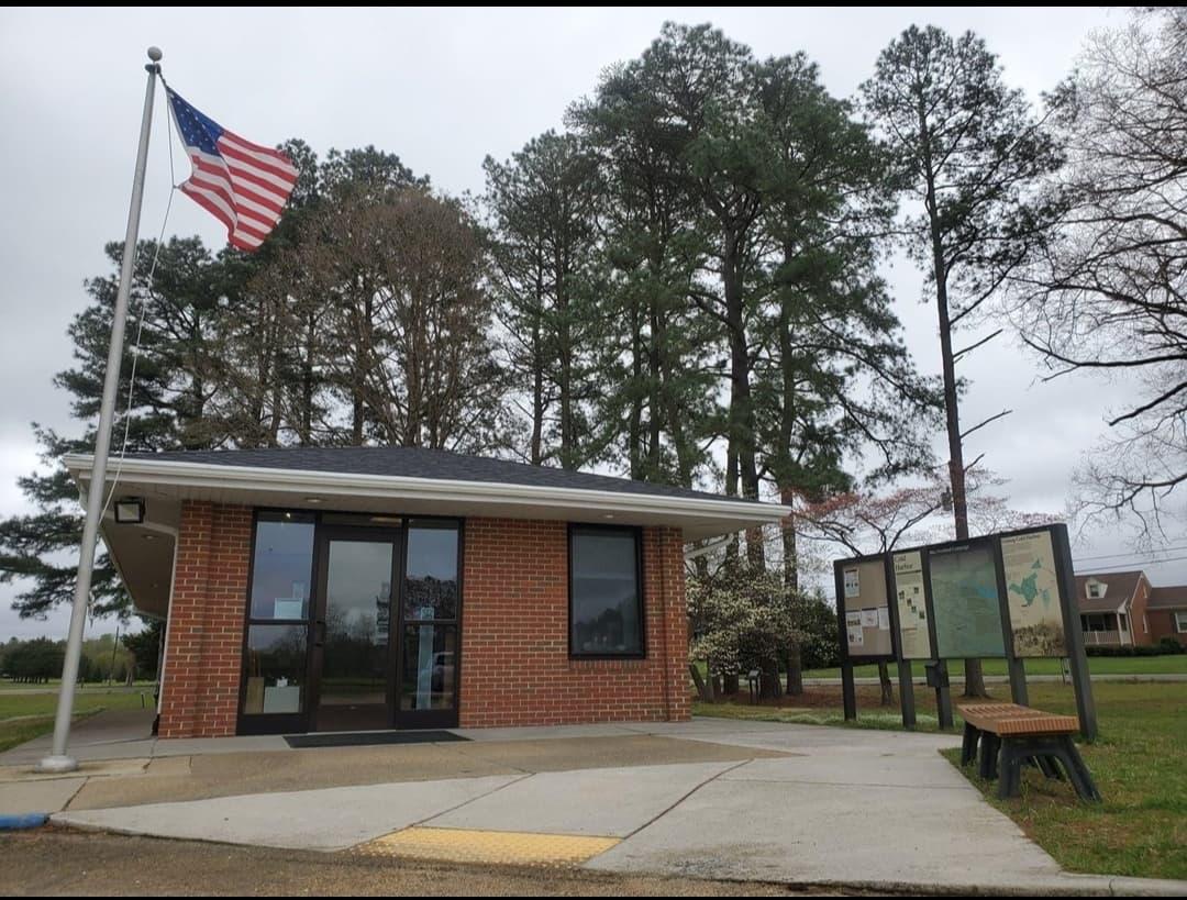A small brick visitor center building beside a flagpole.