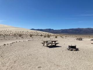 Campsite with picnic table with sand dunes in the background