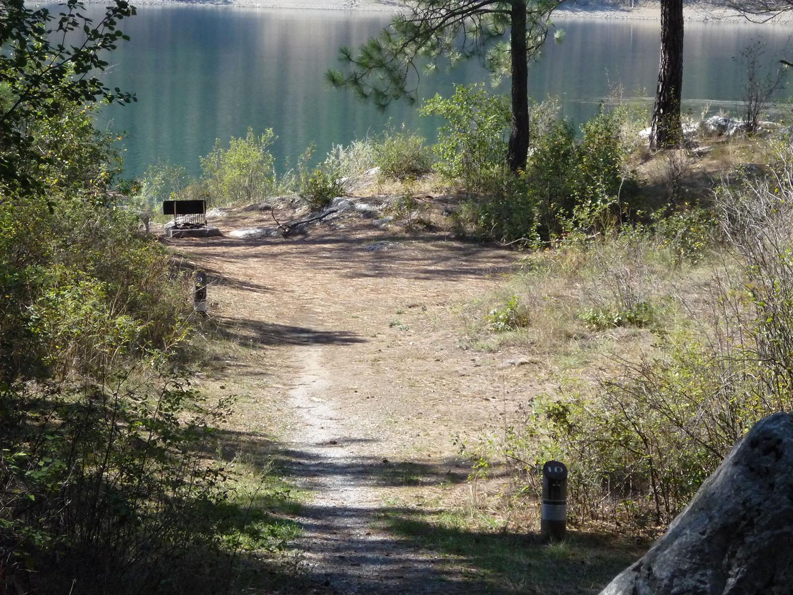 a primitive path leads between two campsite markers to the water's edge