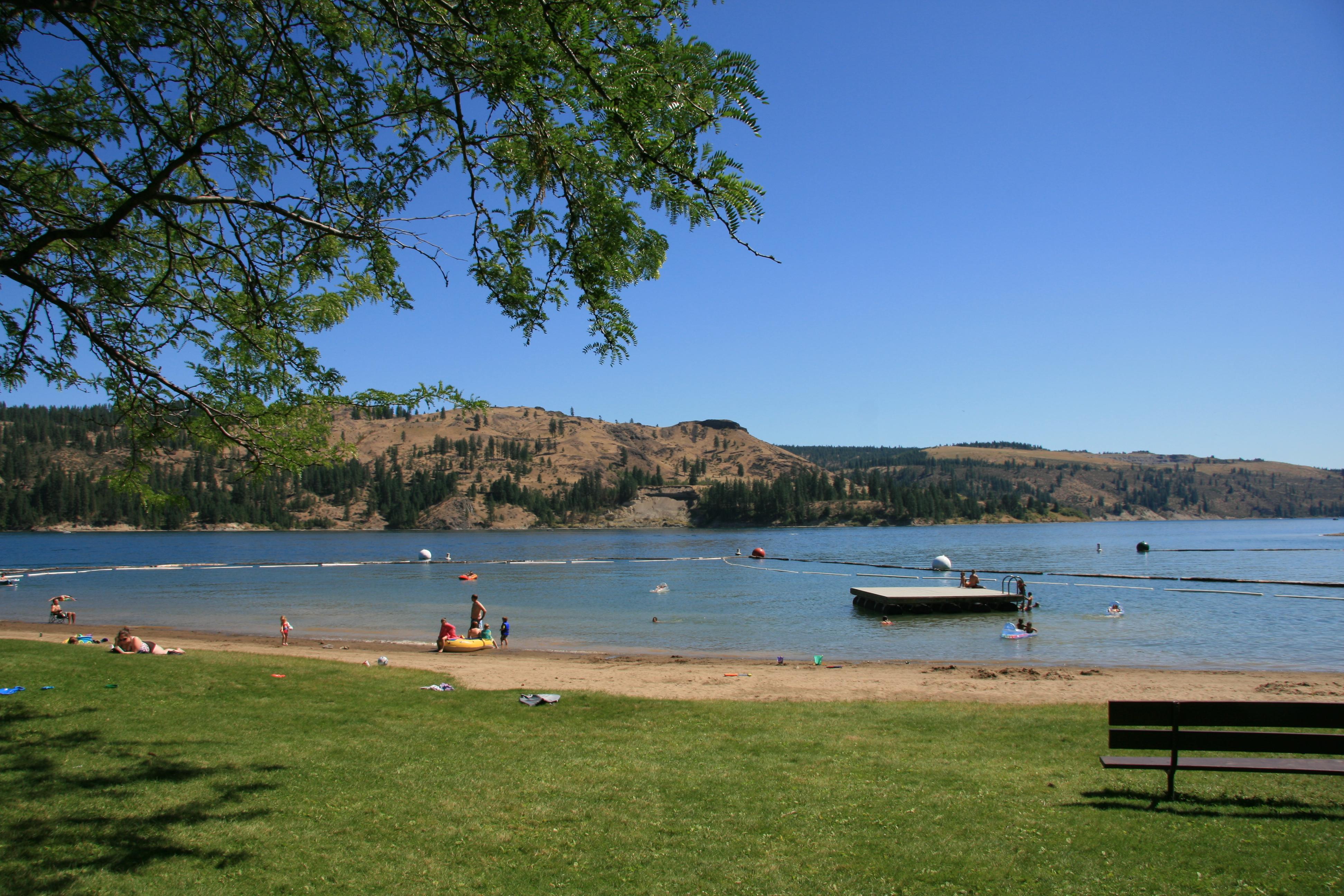 Swim beach with swim dock from the shore. Spokane arm of Lake Roosevelt in the background.