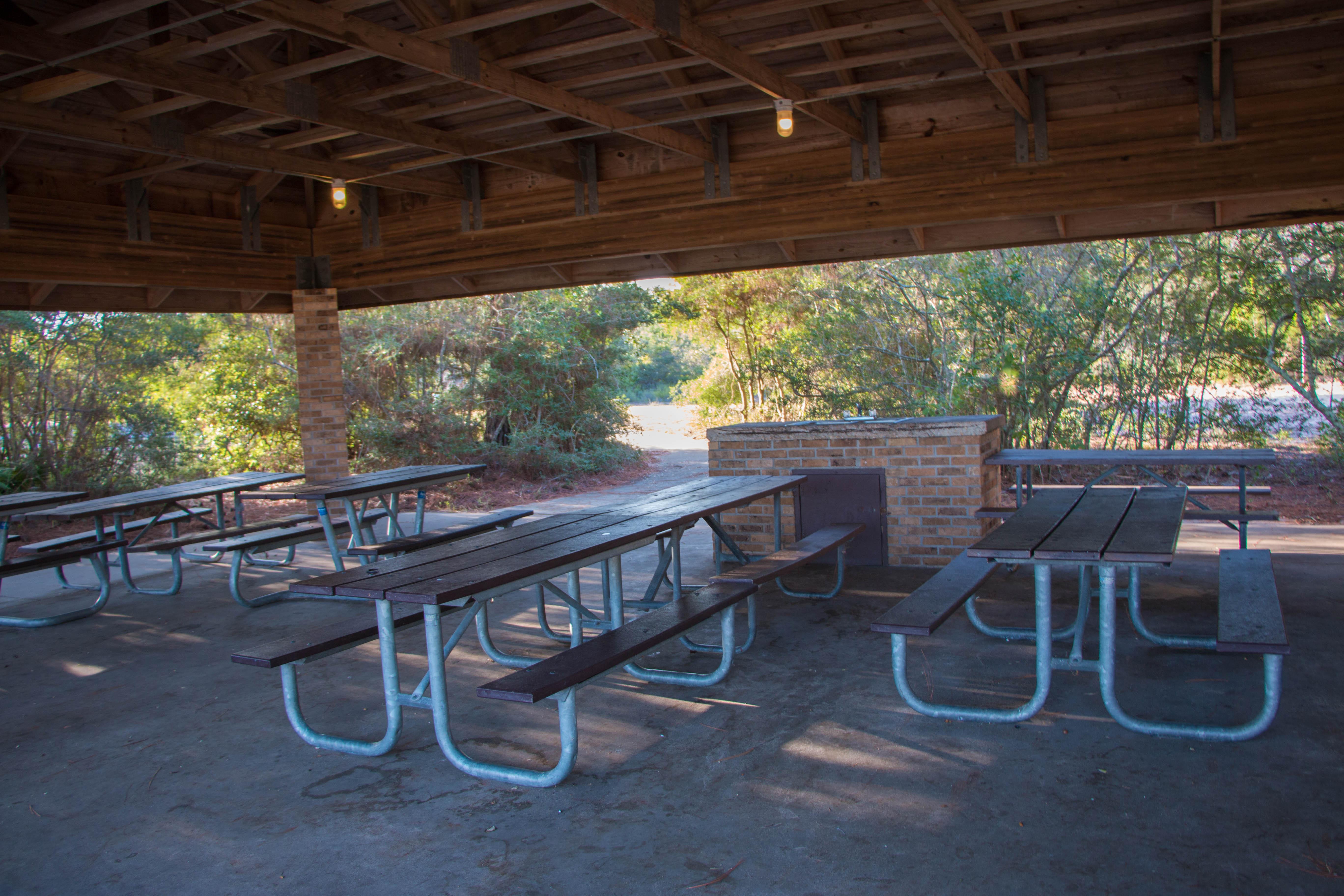 Picnic tables sit under a shaded pavilion.