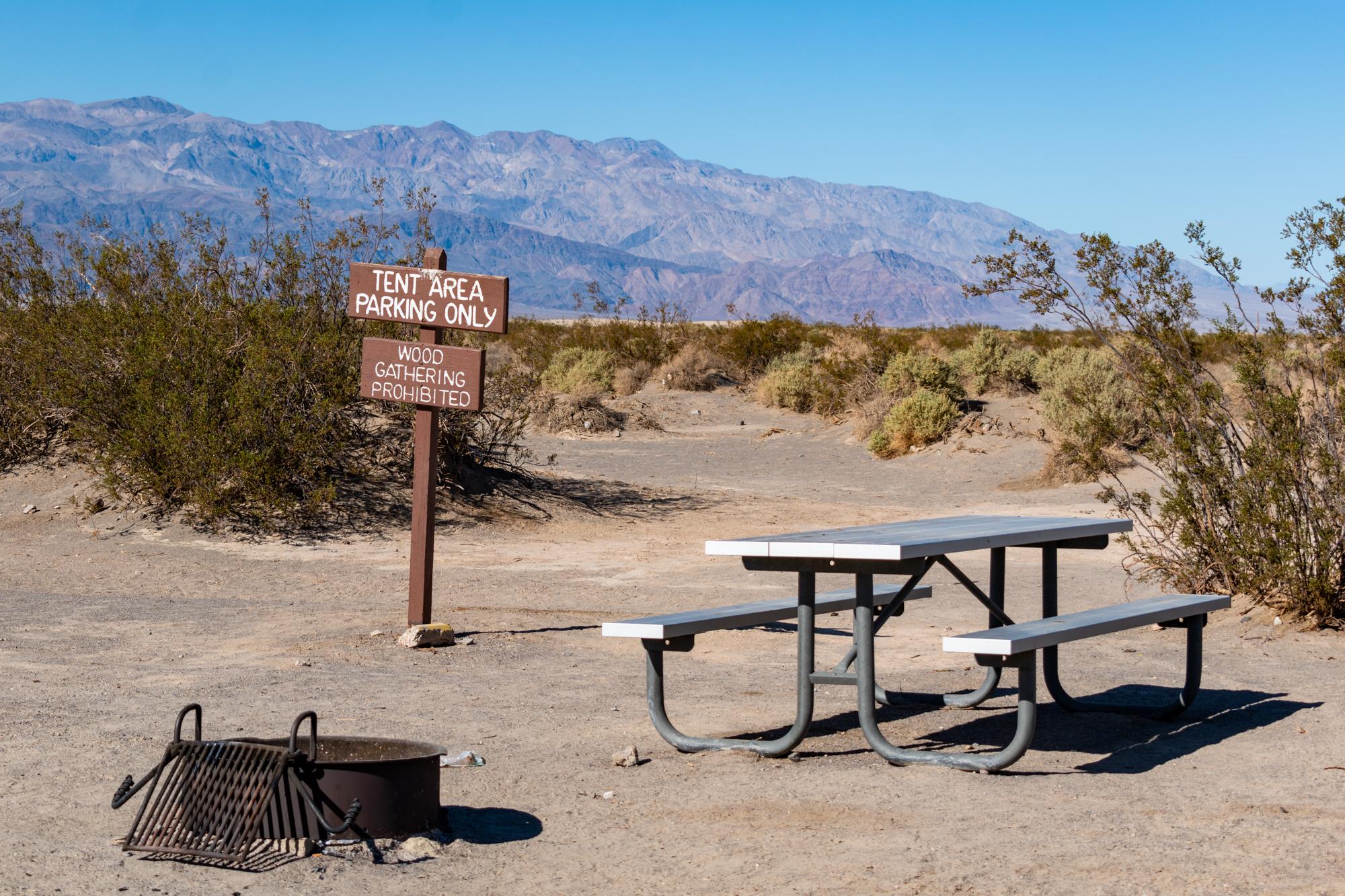 Wooden sign on post reads Tent Area Parking Only. Wood Gathering Prohibited.
