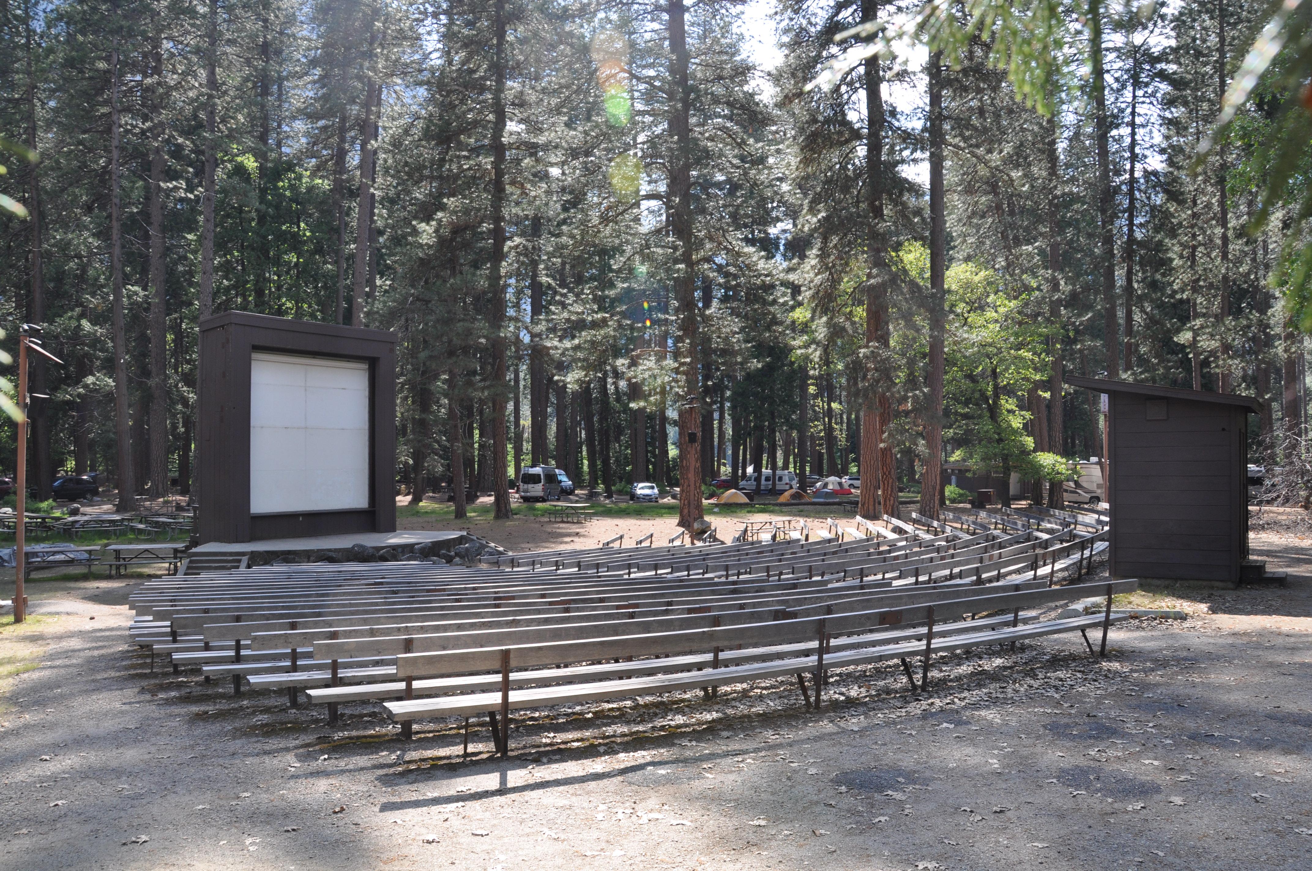 Empty amphitheater in campground with benches and a screen and stage