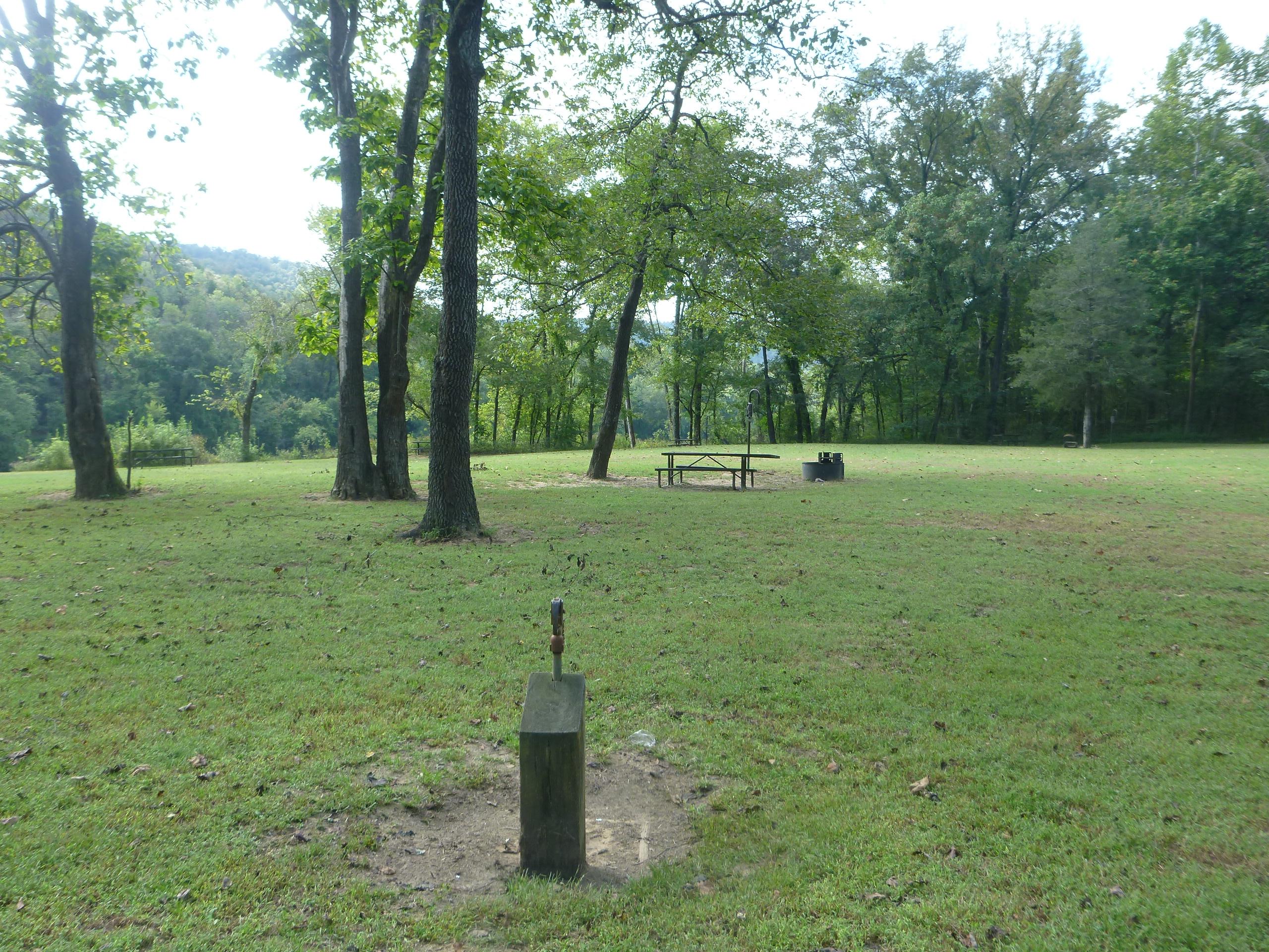 A water hydrant and two campsites with picnic tables and fire rings at Rush Campground.
