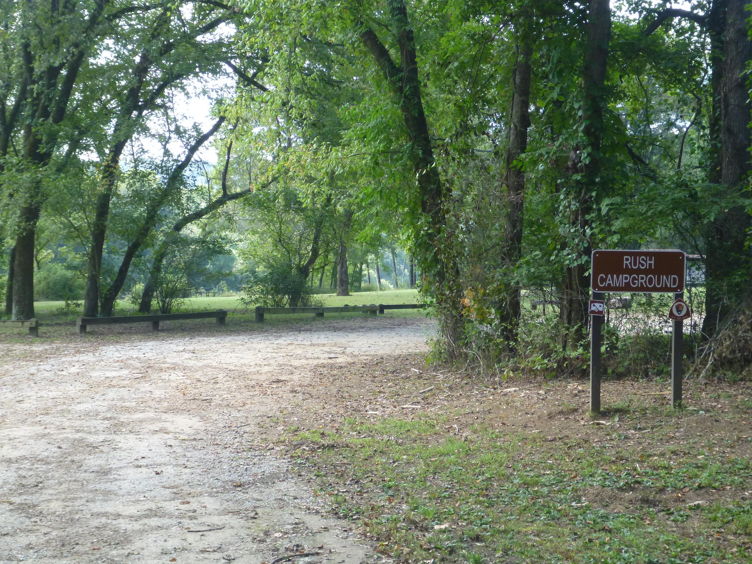 Rush Campground entrance sign and gravel parking lot.