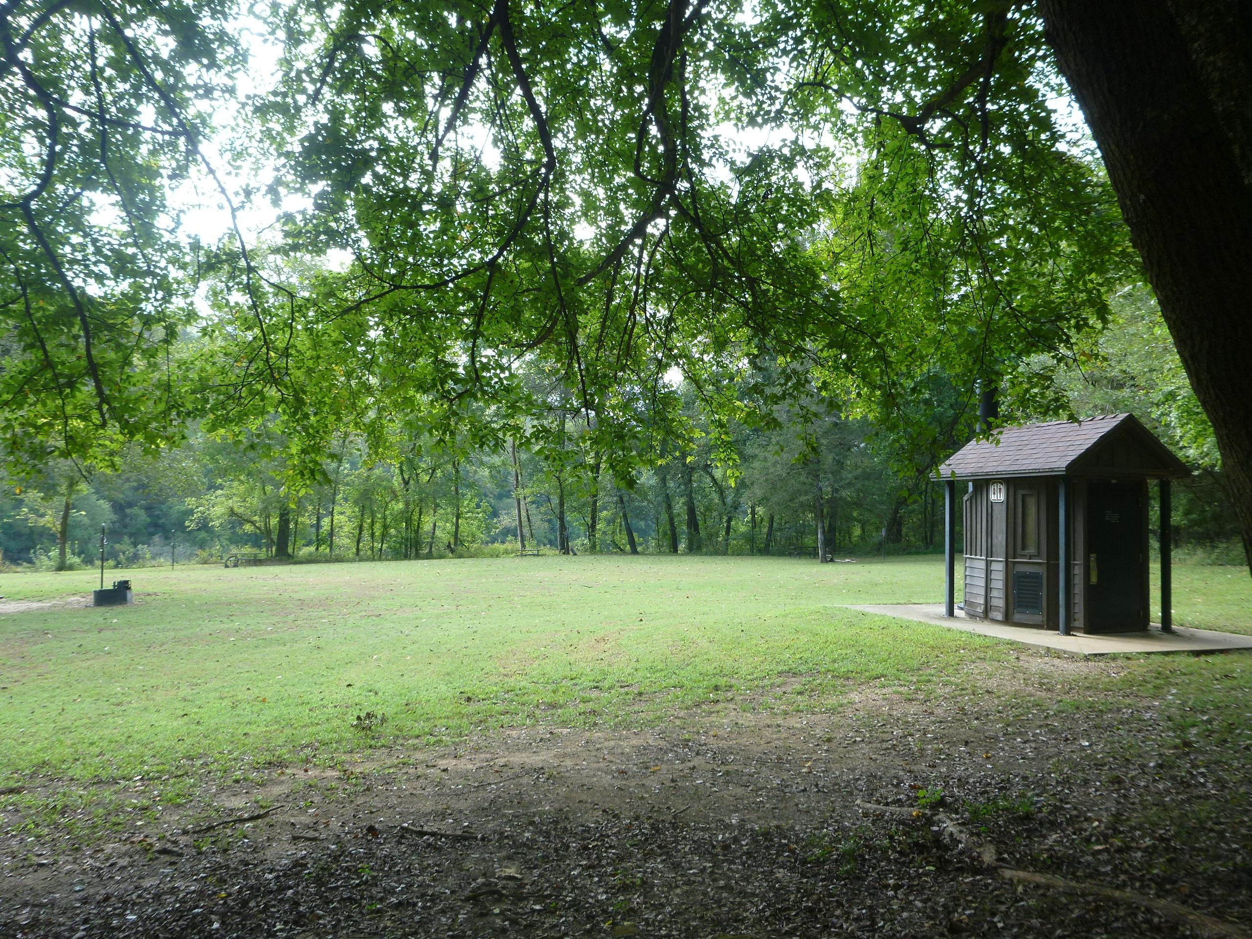 Vault restroom facility in Rush Campground with shade trees nearby.